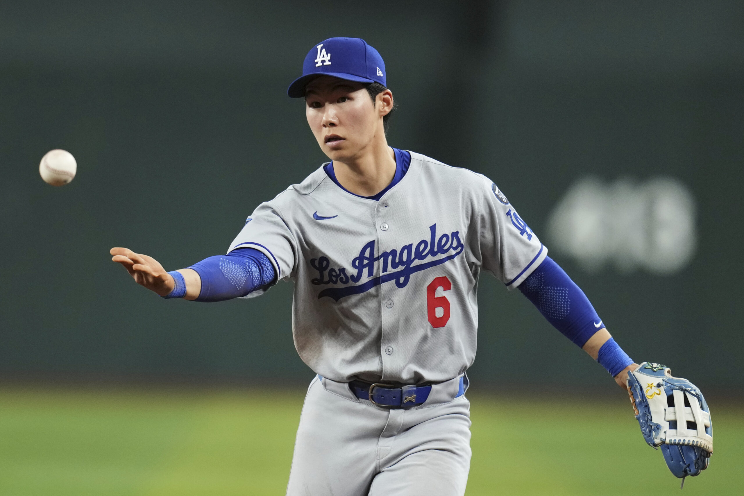 Dodgers second baseman Hyeseong Kim tosses the ball to first...