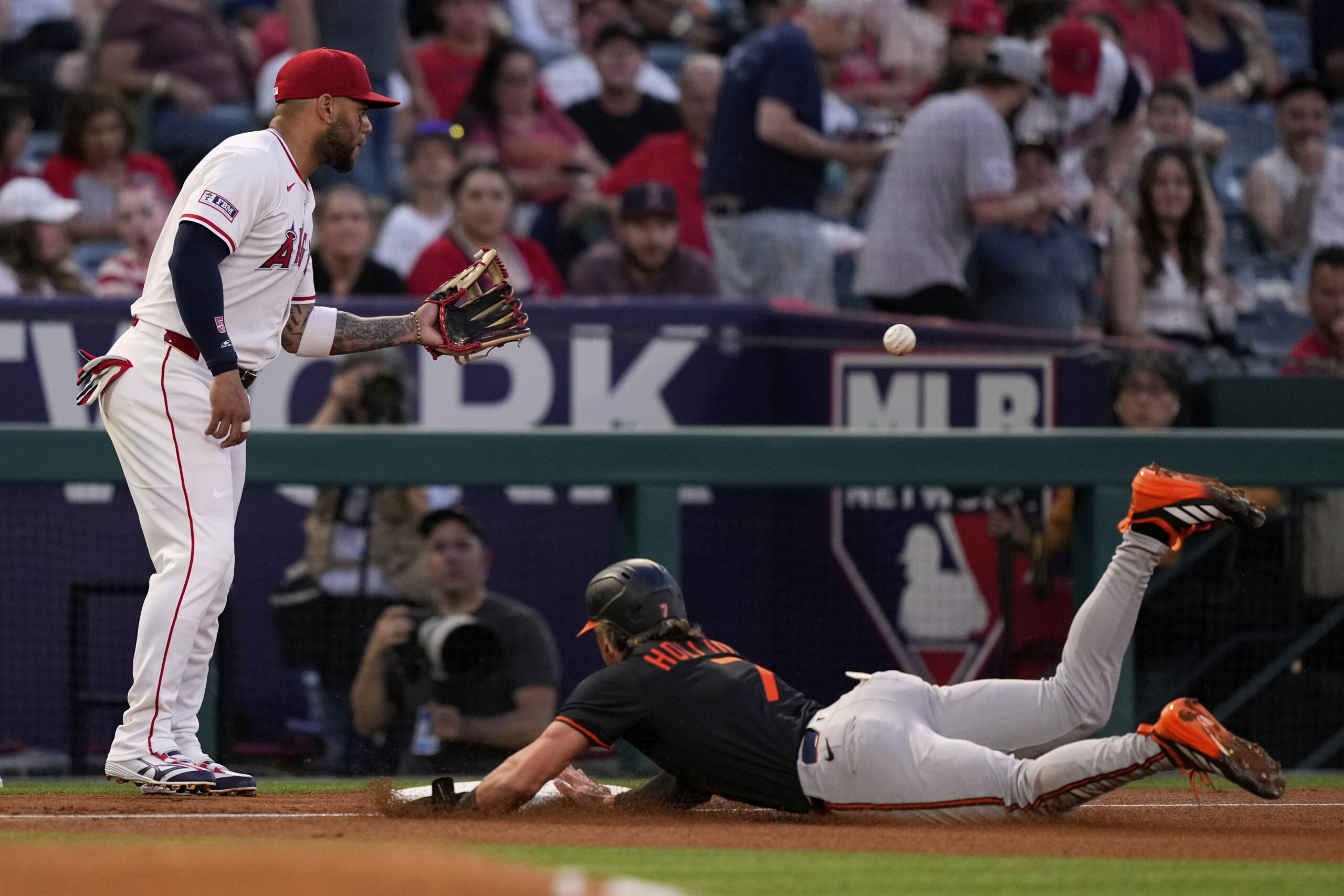 The Baltimore Orioles’ Jackson Holliday, right, dives into third on...