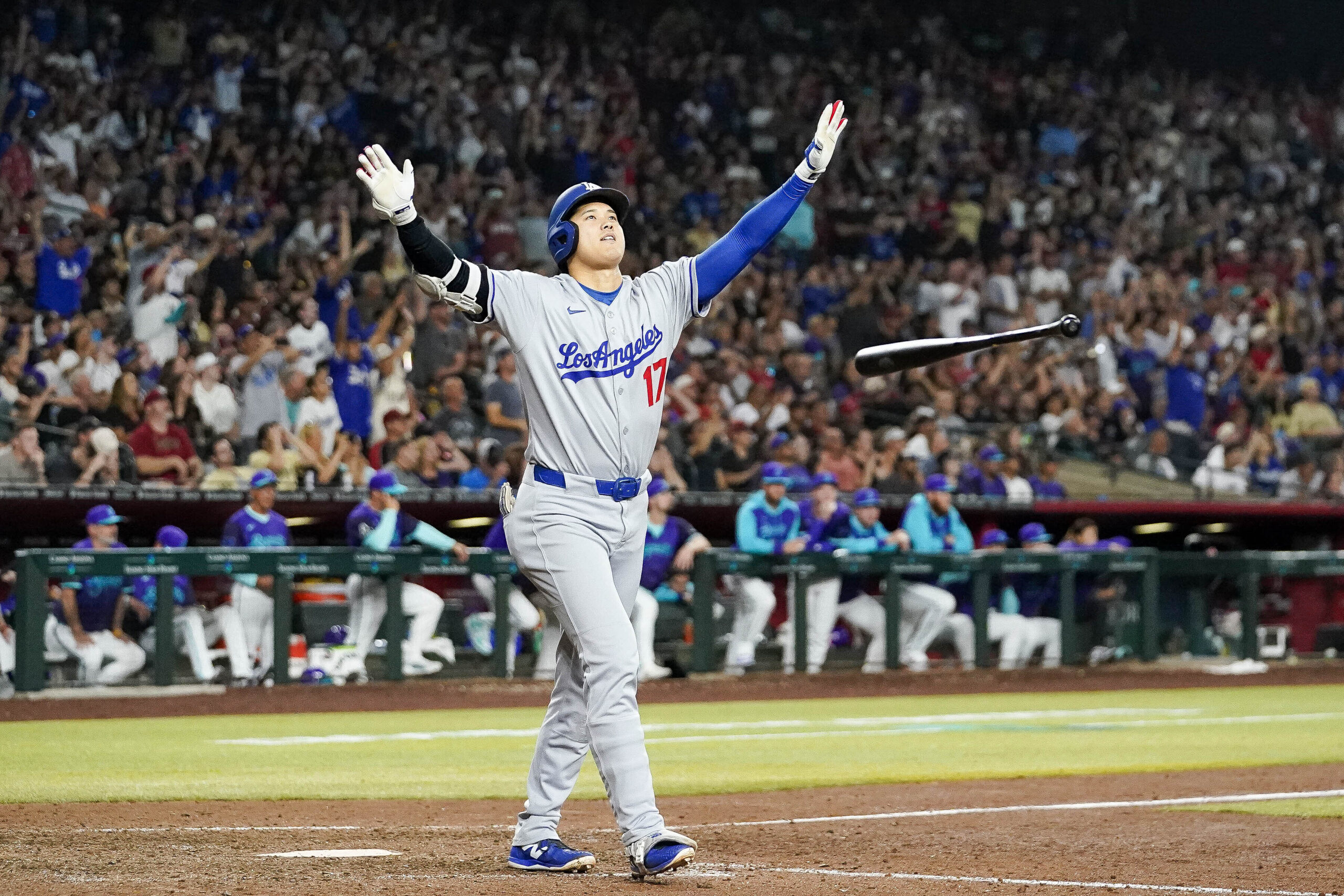 Dodgers star Shohei Ohtani tosses his bat as he begins...