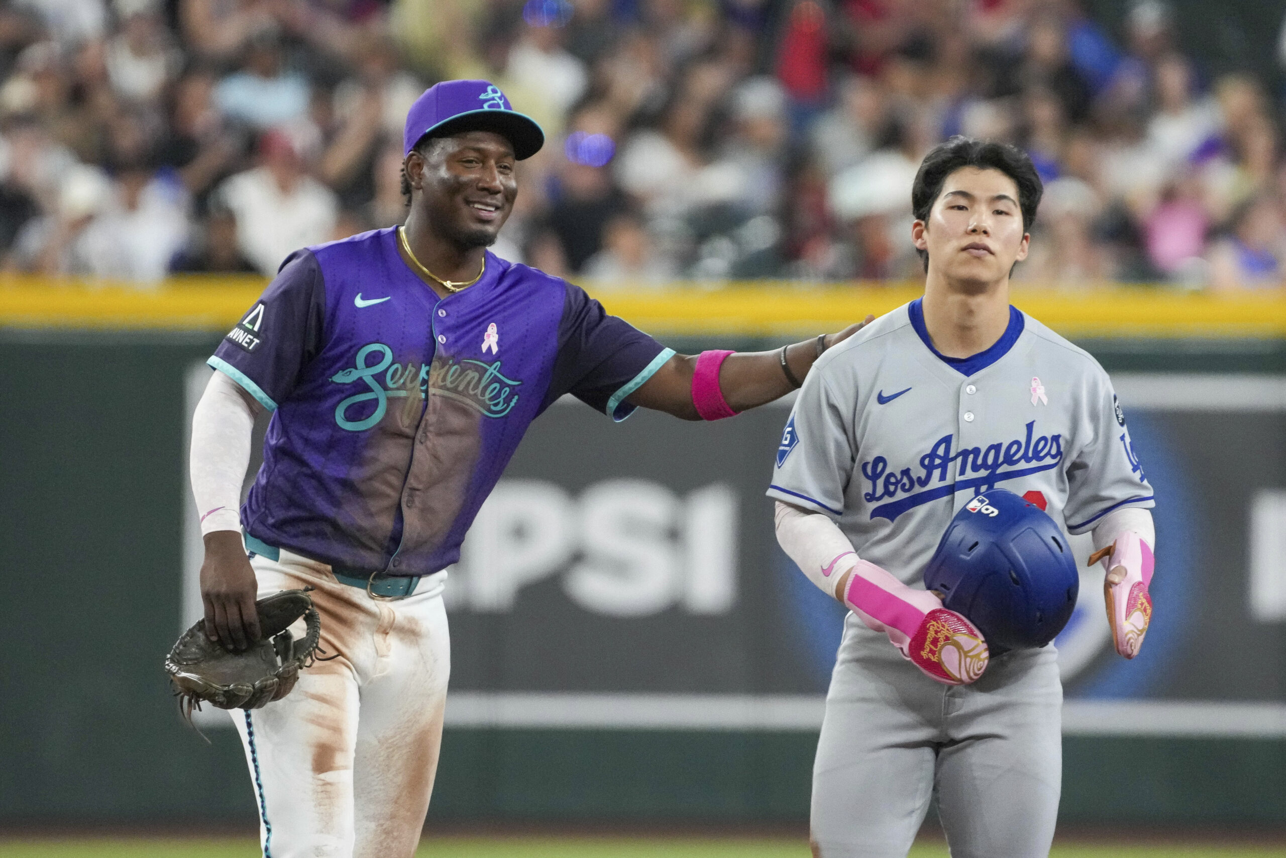 Arizona Diamondbacks shortstop Geraldo Perdomo, left, gives Dodgers’ Hyeseong Kim,...
