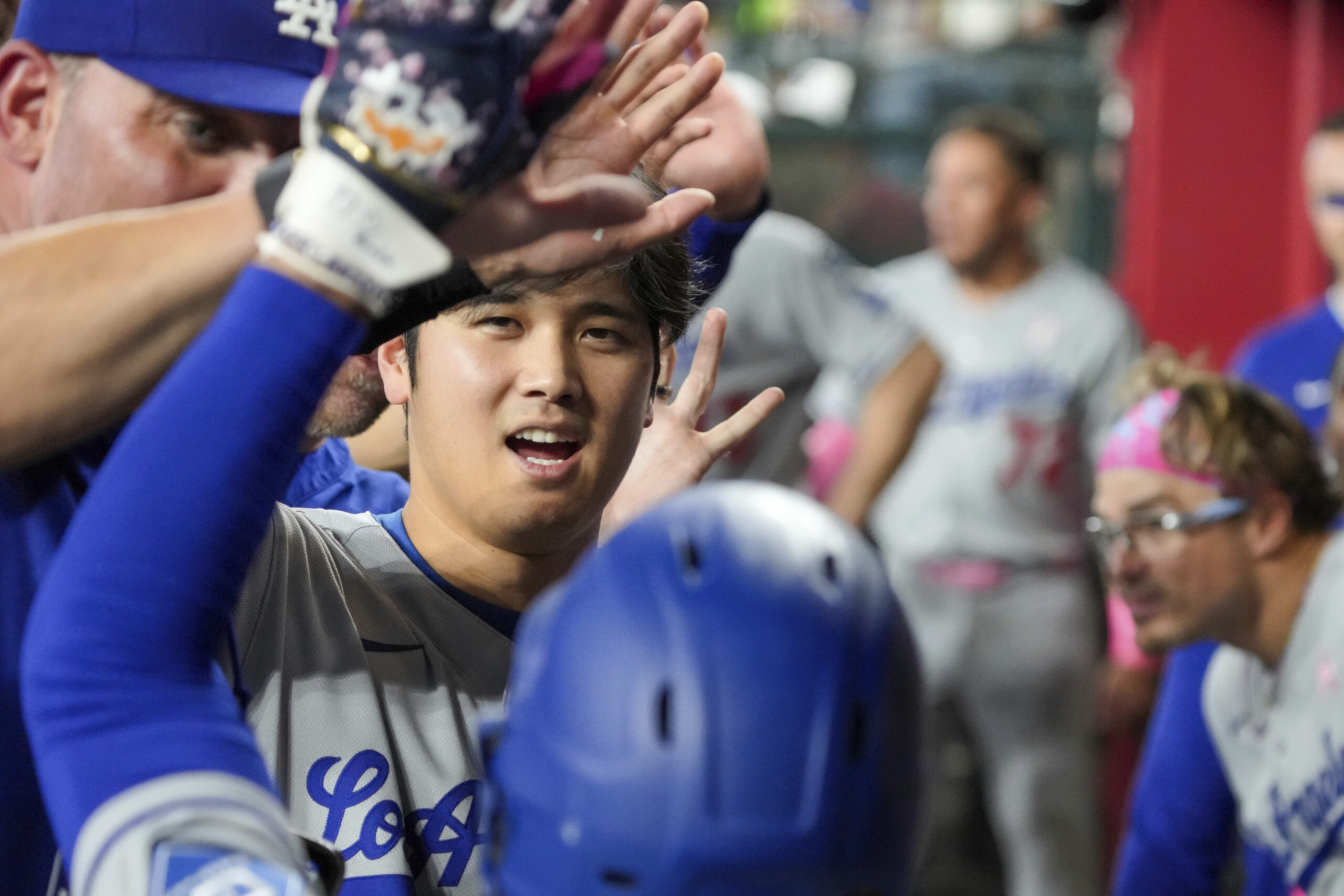 Dodgers’ Shohei Ohtani, center, waits to high-five Mookie Betts, foreground,...