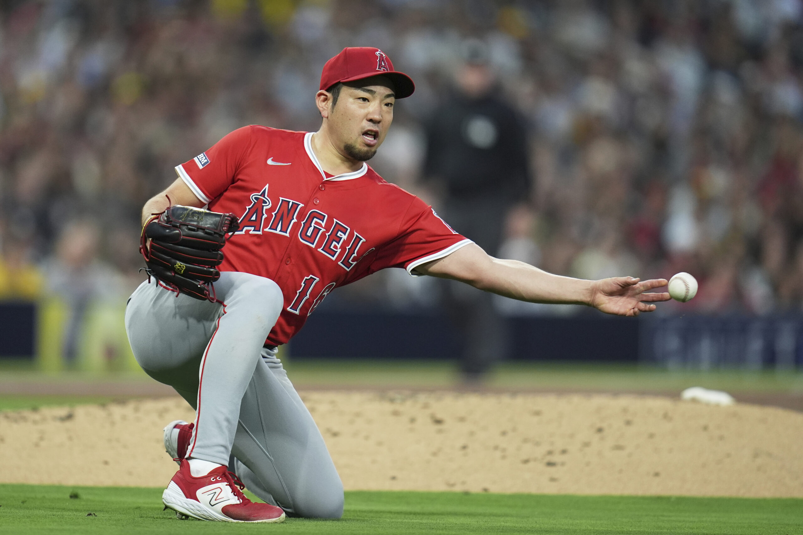 Angels starting pitcher Yusei Kikuchi overthrows first base after dropping...