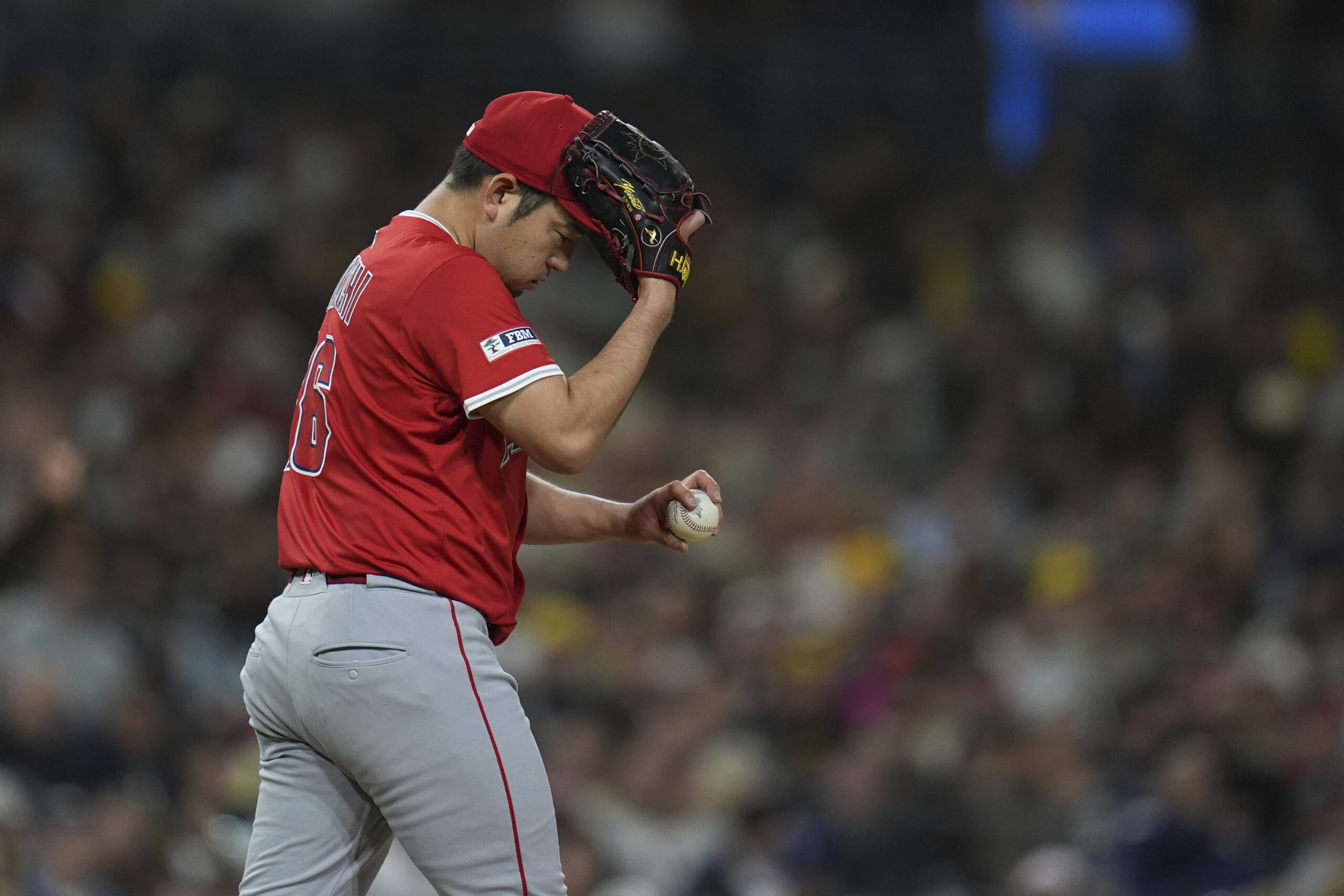 Angels starting pitcher Yusei Kikuchi adjusts his hat with his...