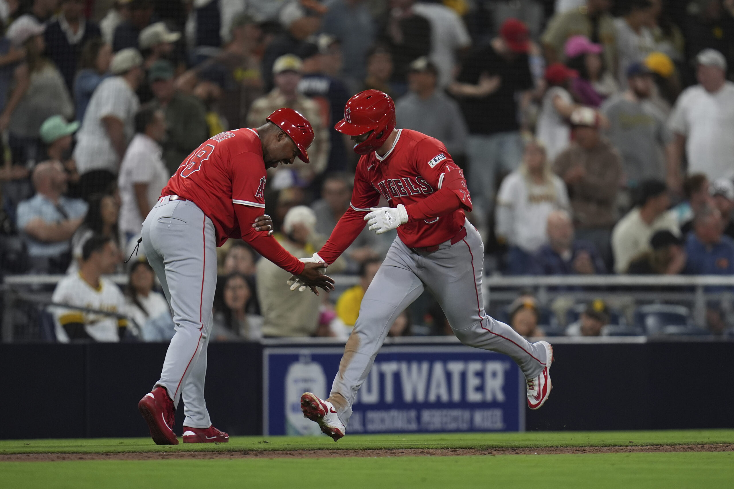 The Angels’ Taylor Ward, right, celebrates with third base coach...