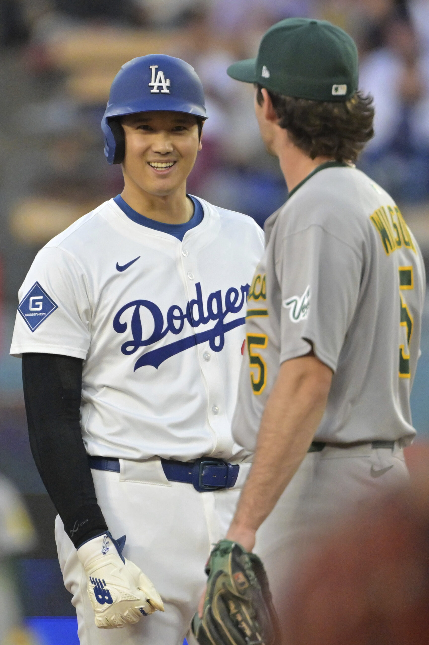 Dodgers star Shohei Ohtani talks with the A’s shortstop Jacob...