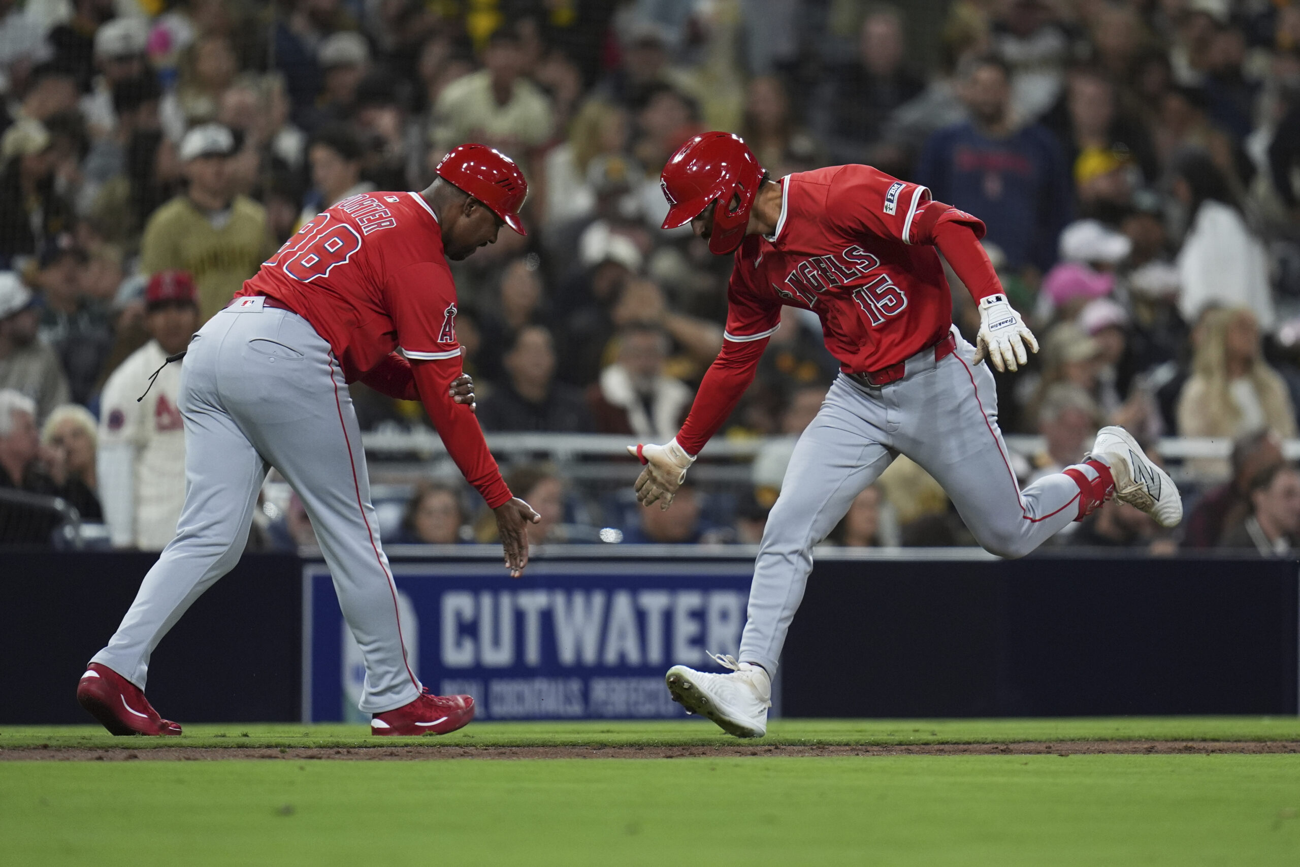 The Angels’ Matthew Lugo, right, celebrates with third base coach...