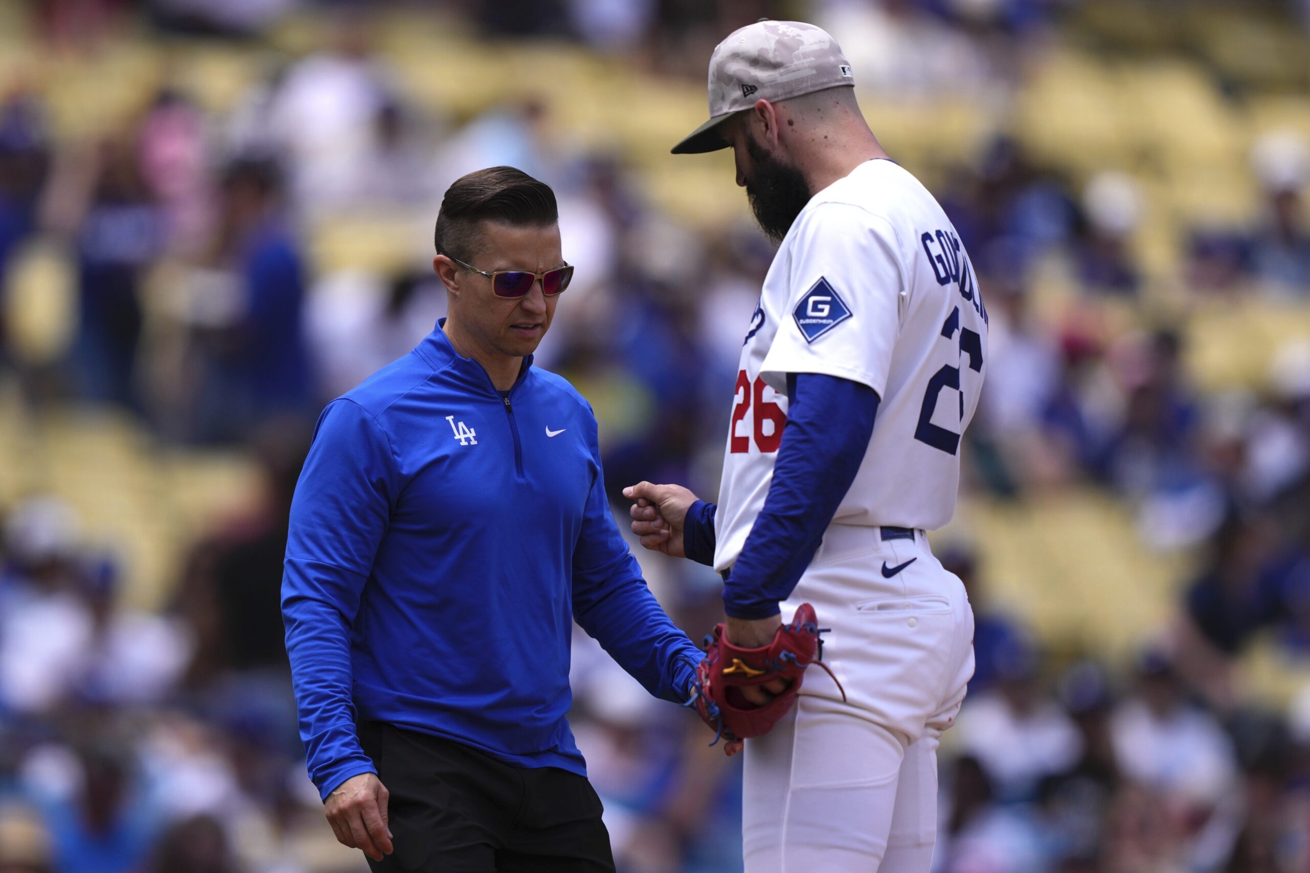 Dodgers starting pitcher Tony Gonsolin right, talks to a trainer...