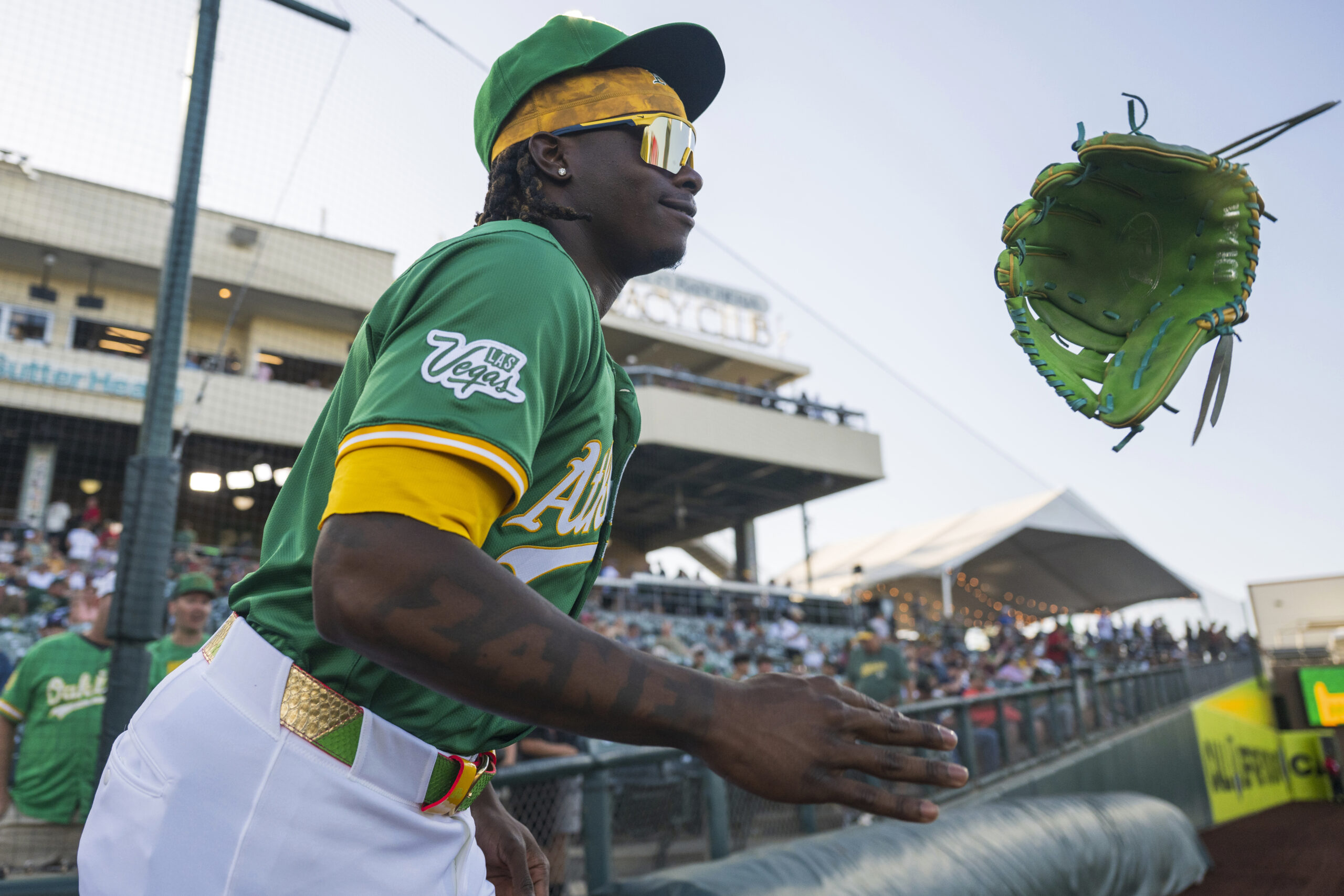 Athletics outfielder Lawrence Butler tosses his glove while running onto...