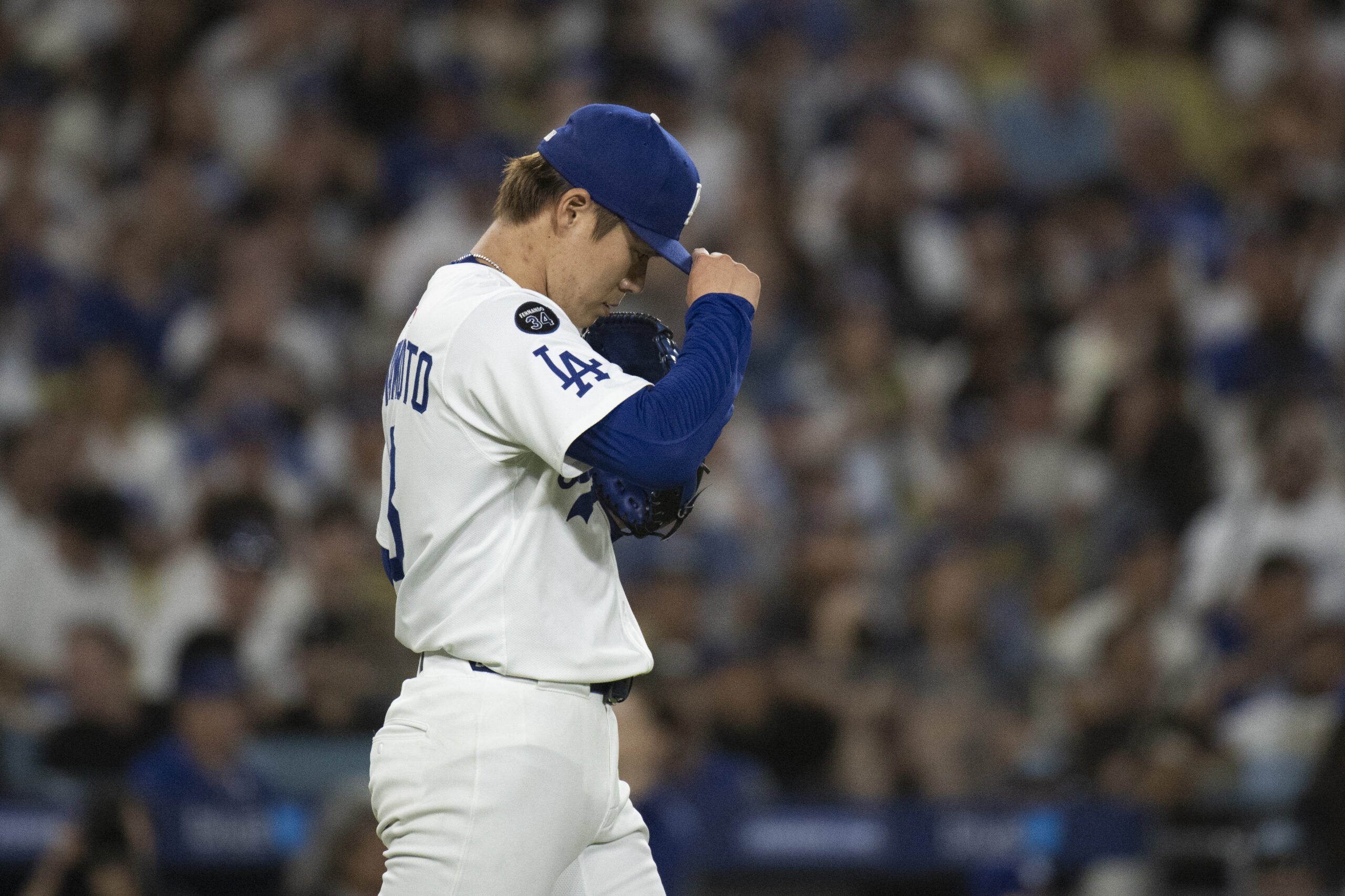 Dodgers starting pitcher Yoshinobu Yamamoto fixes his cap during the...