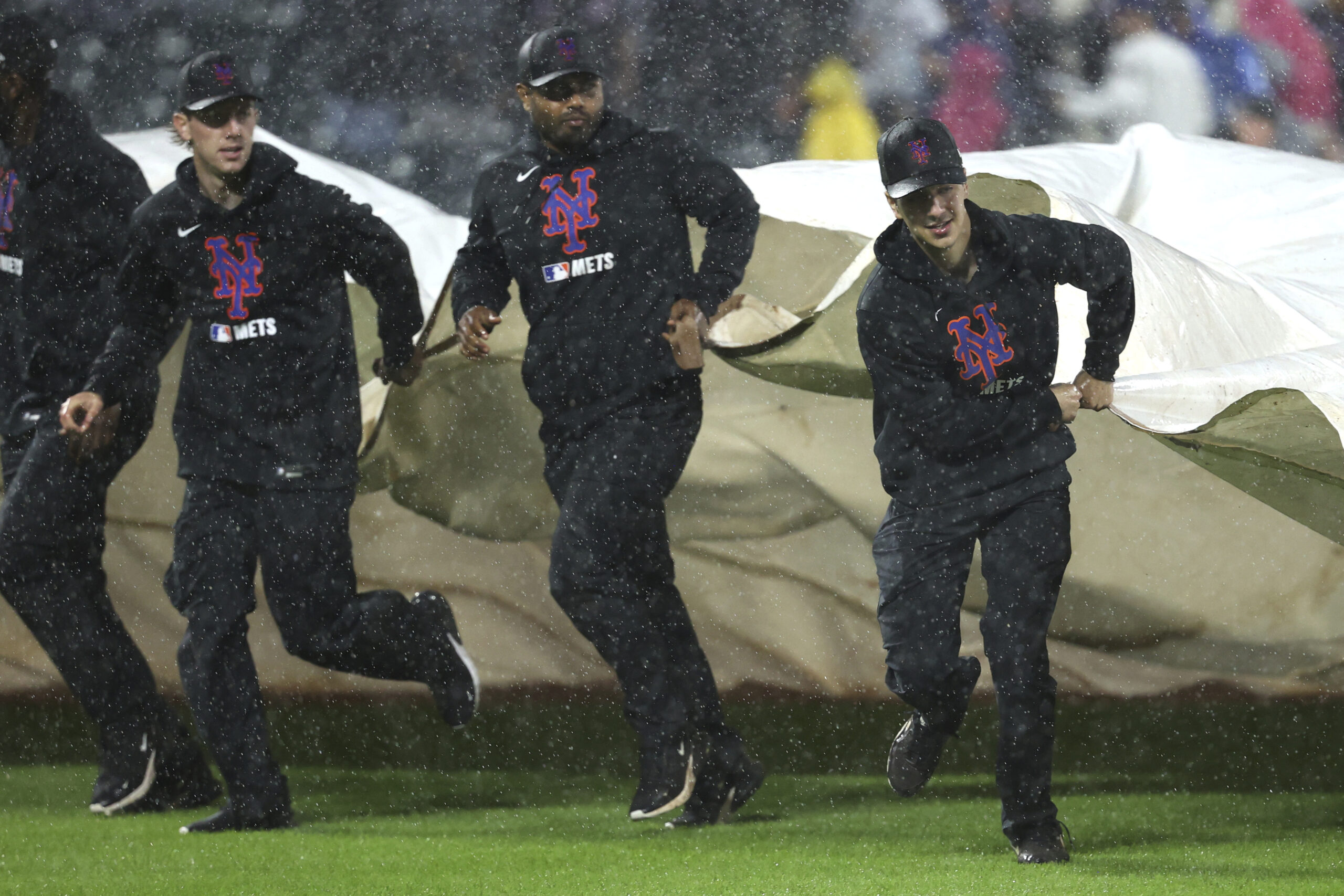 Grounds crew members cover the field during the third inning...