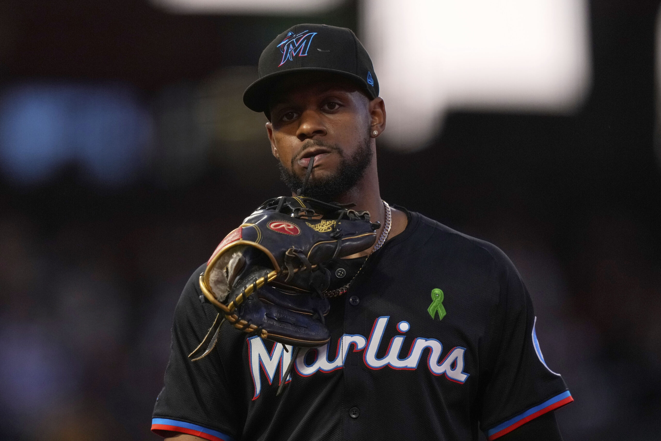 Miami Marlins’ Otto Lopez carries his glove in his teeth...