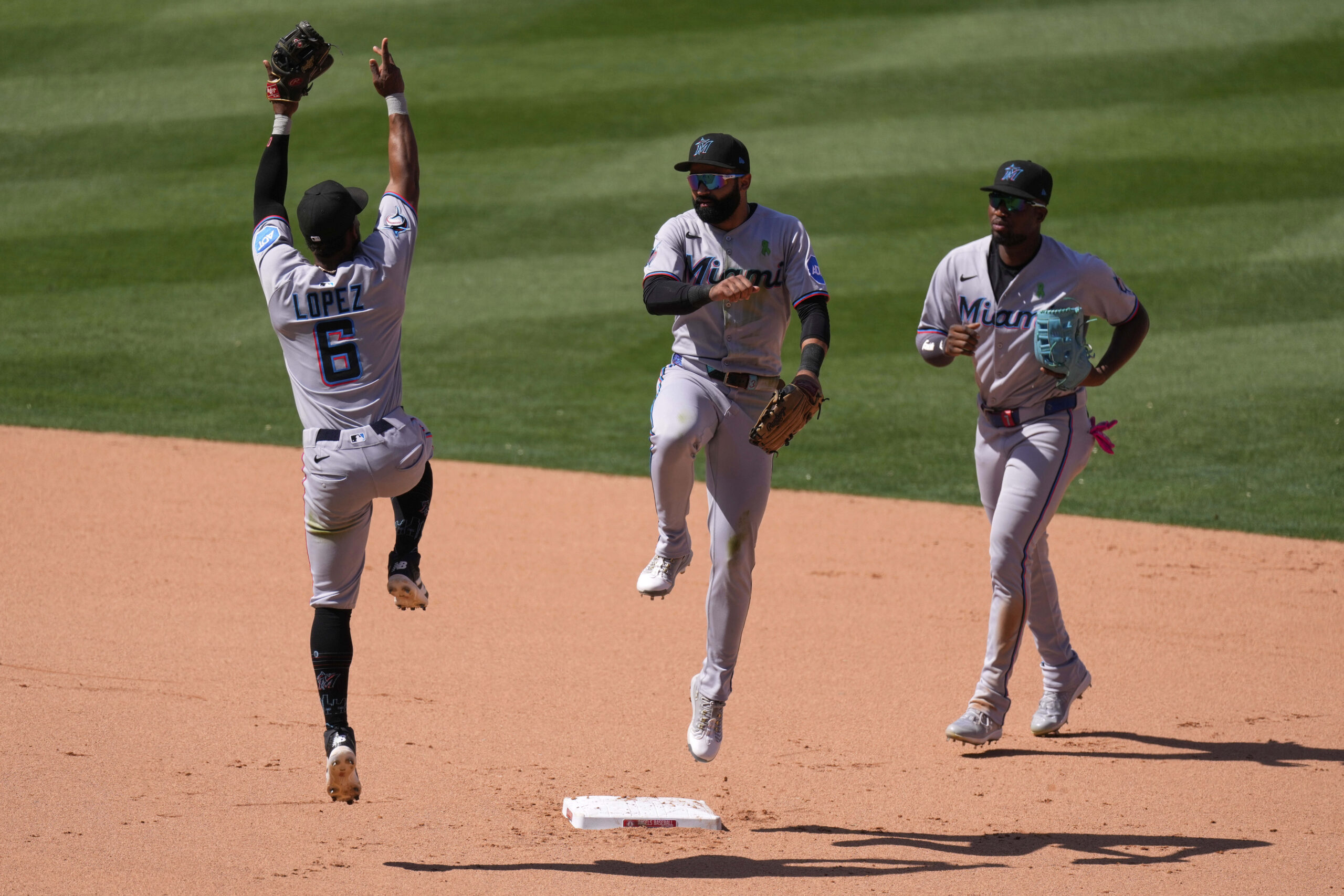 Miami Marlins’ Otto Lopez, left, celebrates with Derek Hill, center,...