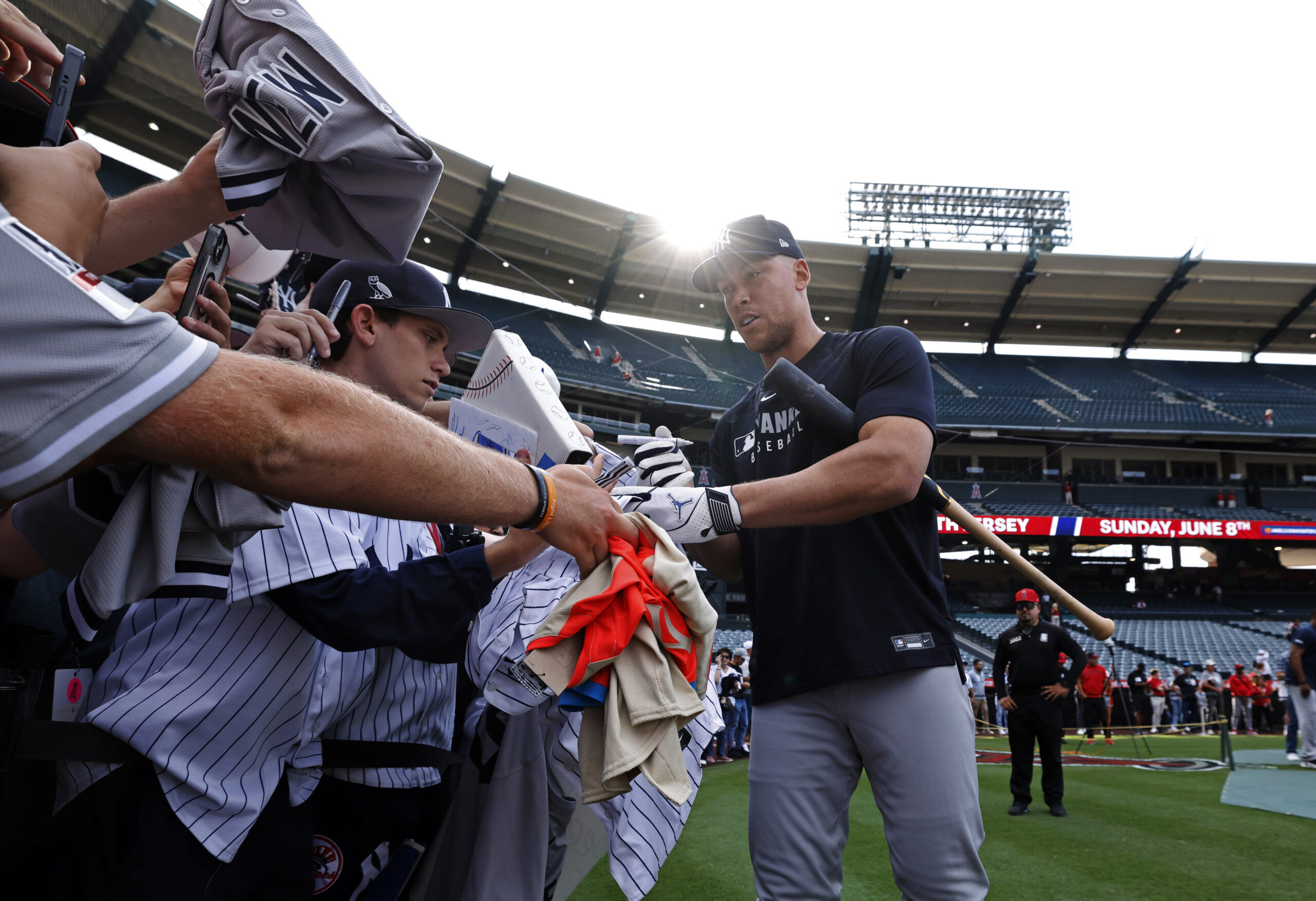 New York Yankees star Aaron Judge, right, signs autographs for...