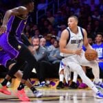 Feb 25, 2025; Los Angeles, California, USA; Dallas Mavericks guard Dante Exum (0) dribbles the ball against Los Angeles Lakers forward Dorian Finney-Smith (17) during the first half at Crypto.com Arena. Mandatory Credit: Gary A. Vasquez-Imagn Images