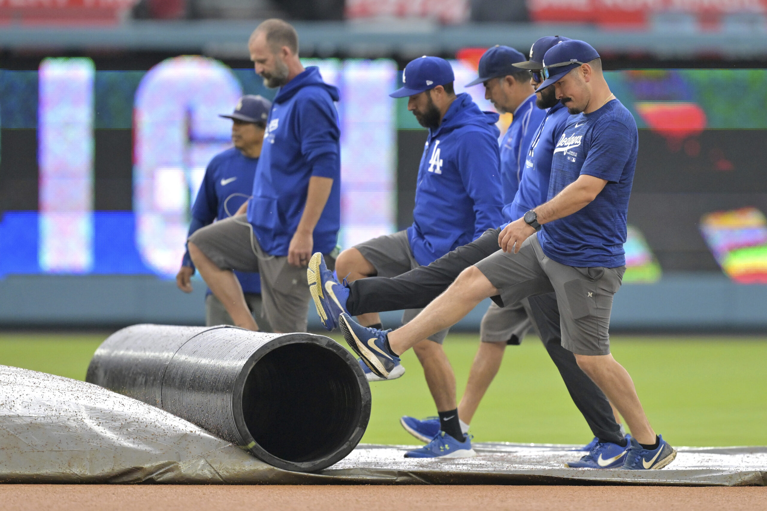 Grounds crew workers roll up a tarp covering the infield...