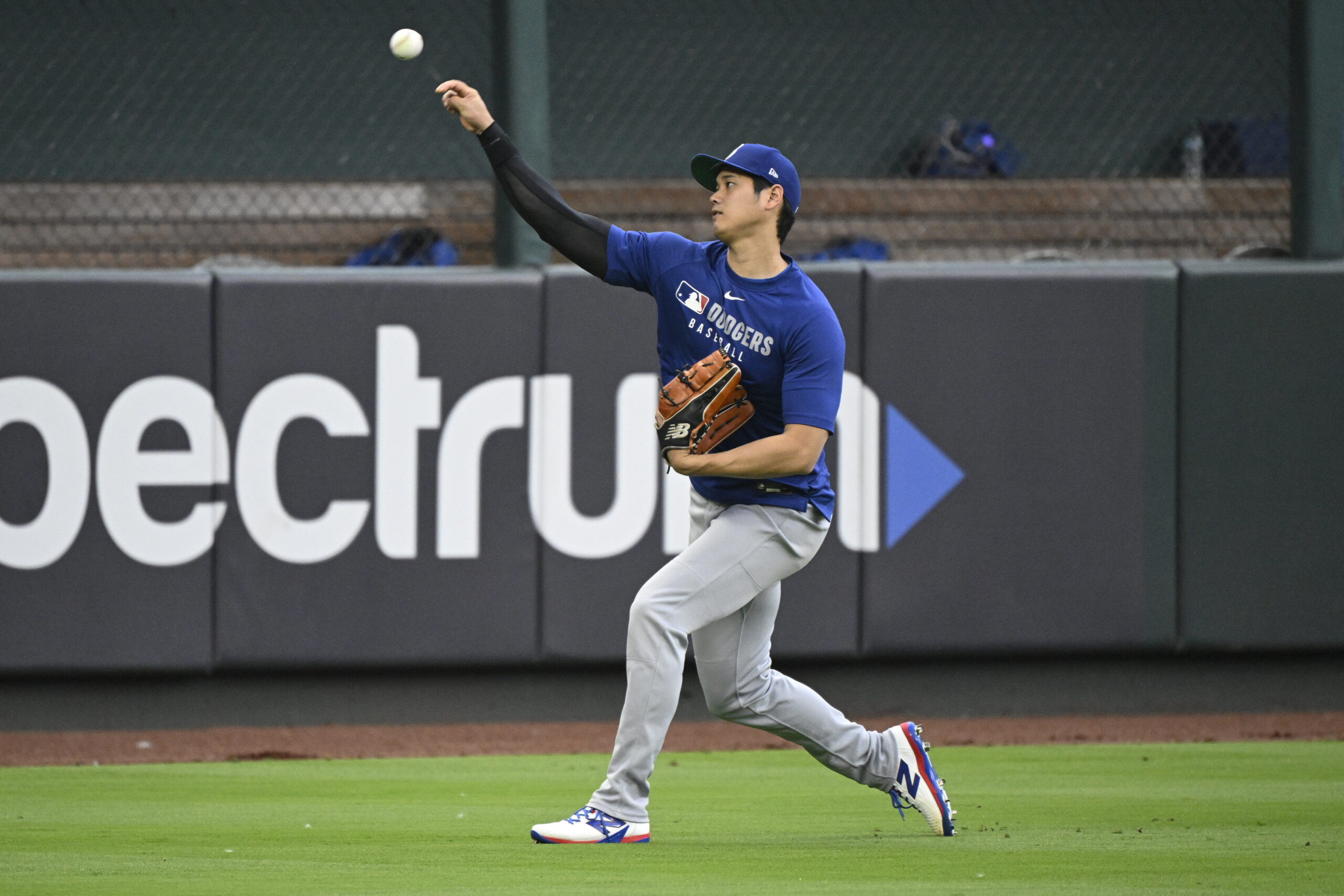 Dodgers star Shohei Ohtani throws in the outfield before a...
