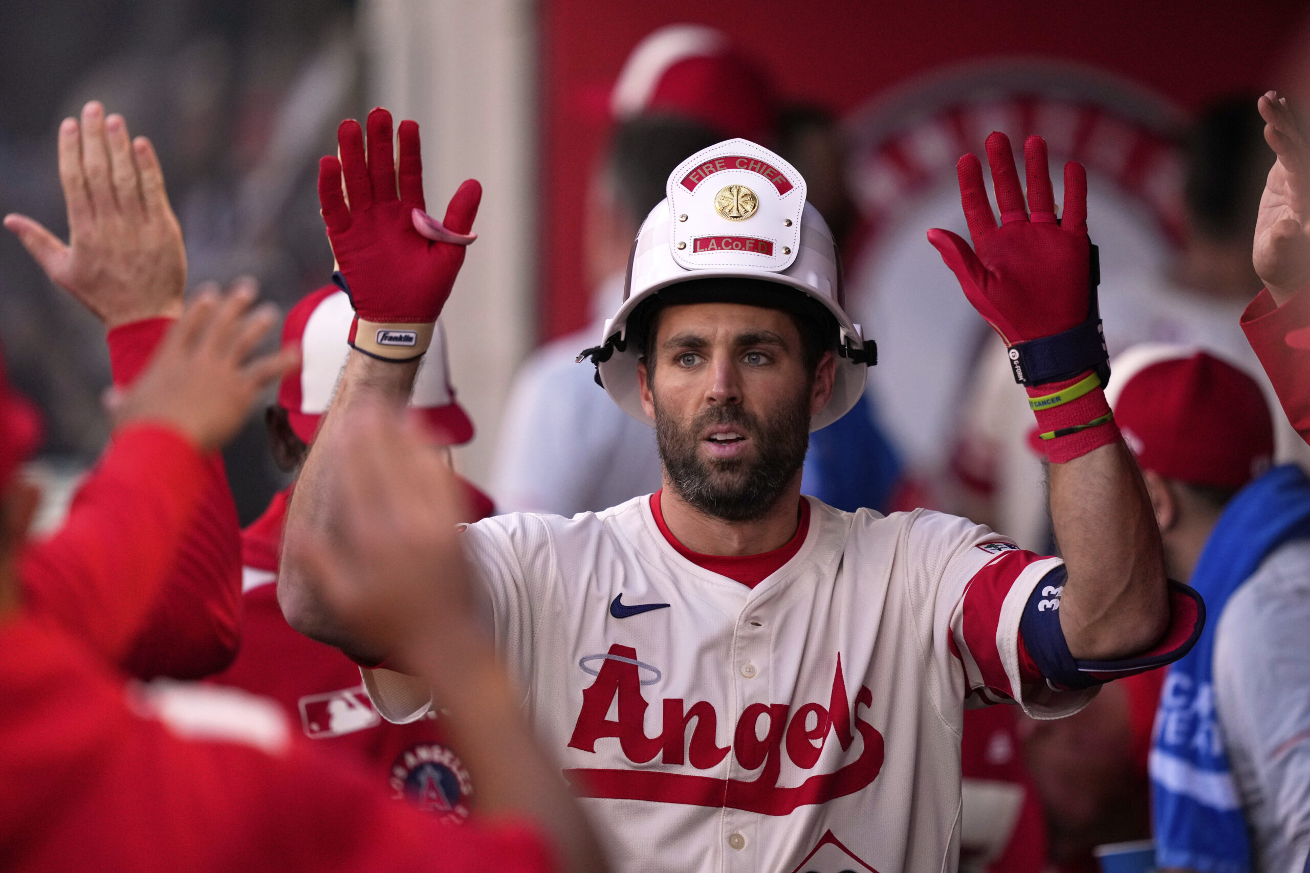 Angels’ Chris Taylor is congratulated by teammates in the dugout...