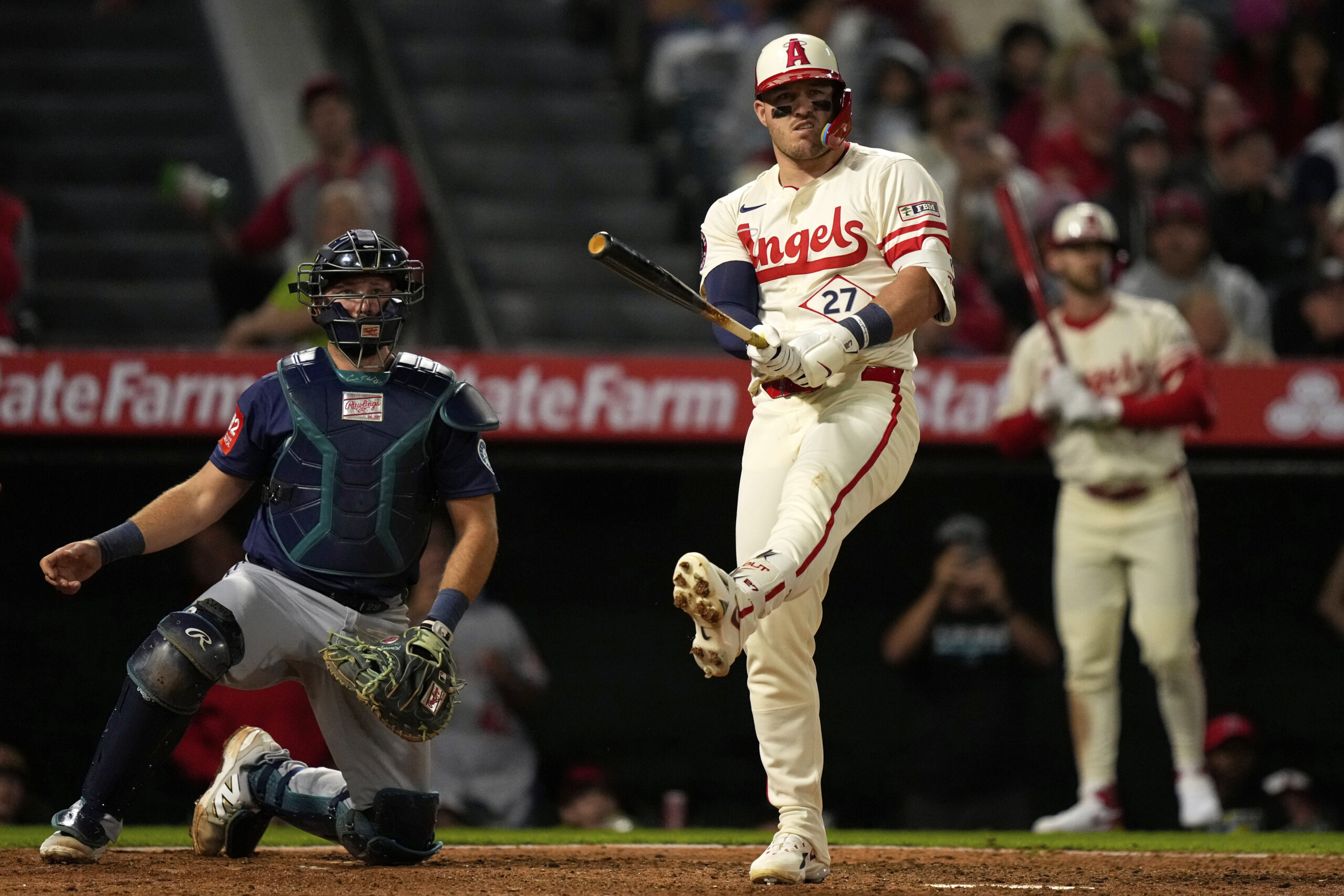 Angels’ Mike Trout, center, gestures after hitting a foul ball...