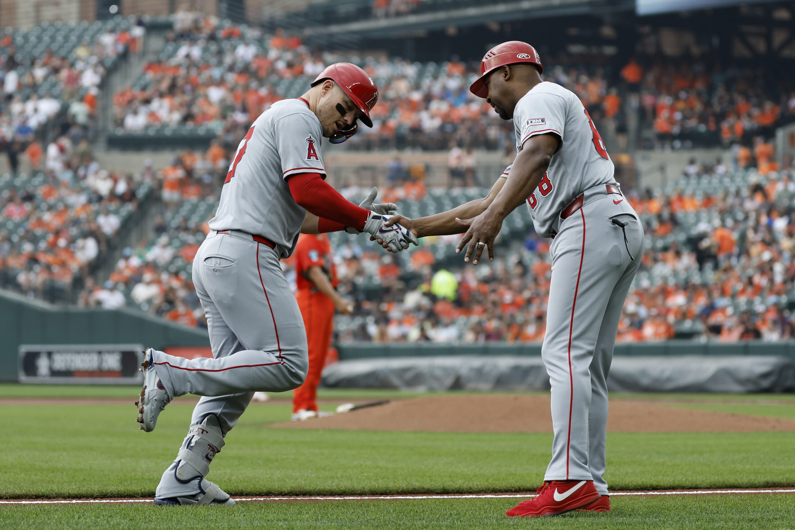 Angels’ Mike Trout, left, is greeted by third base coach...