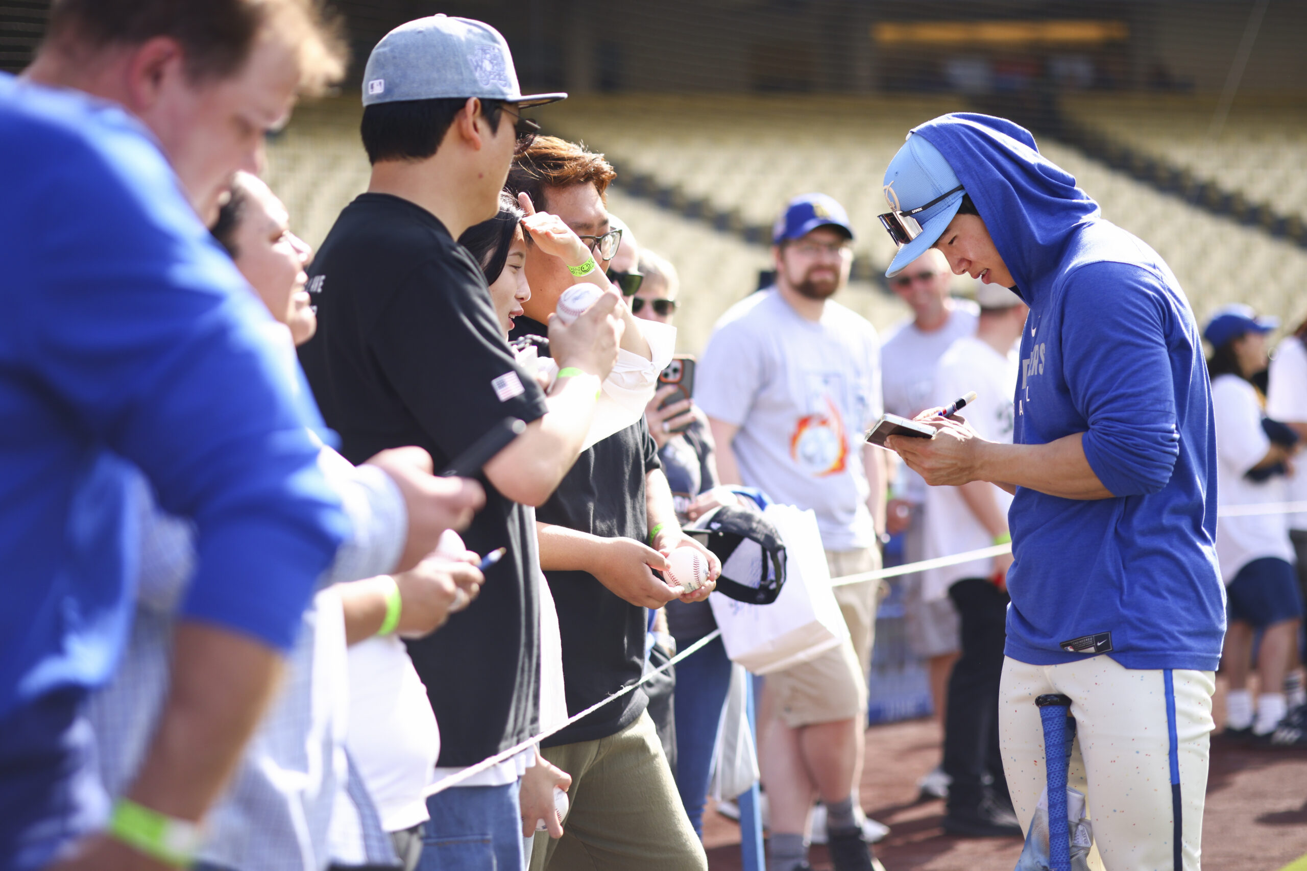 Dodgers’ Hyeseong Kim, right, gives autographs to fans before a...