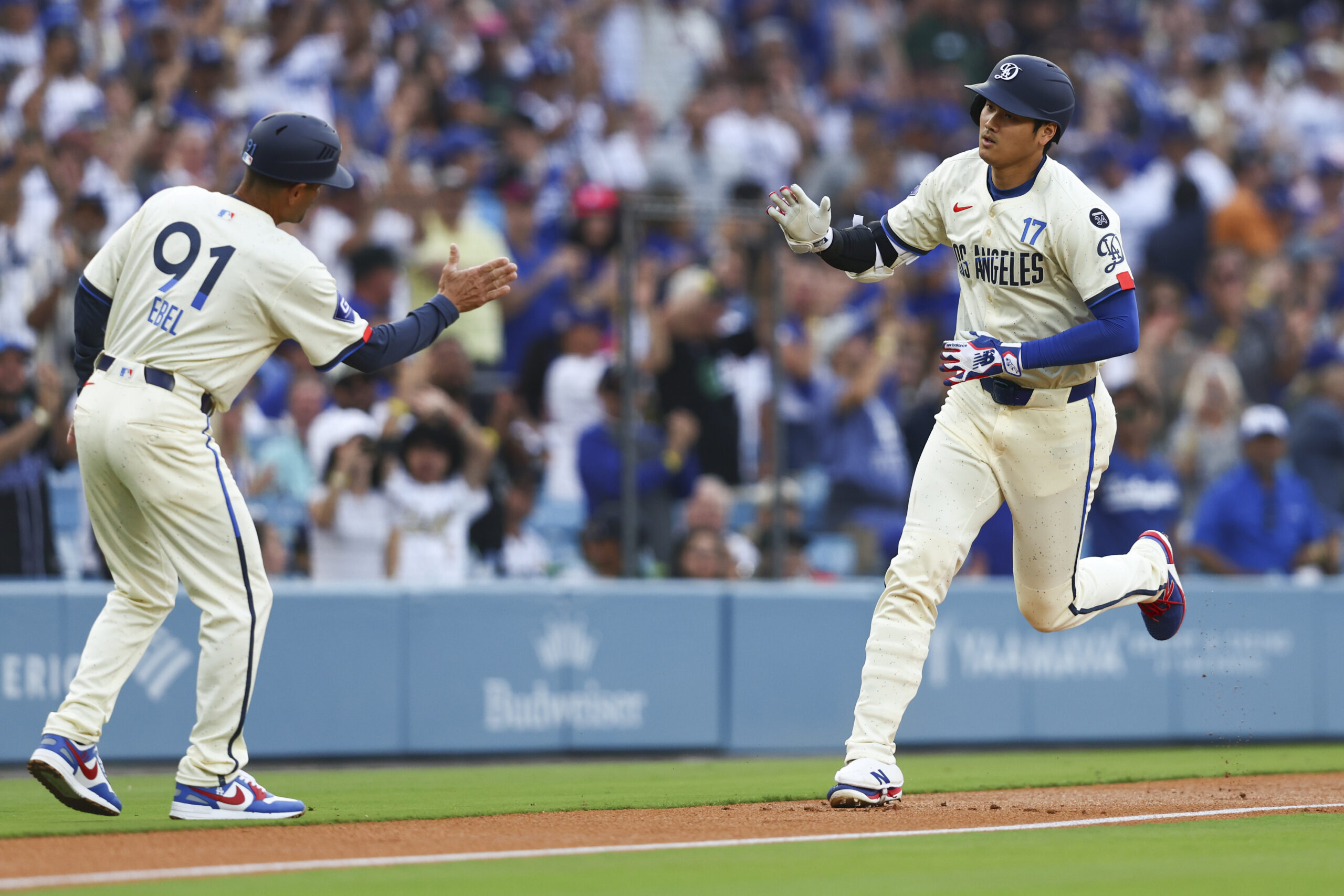 Dodgers designated hitter Shohei Ohtani celebrates with third base coach...
