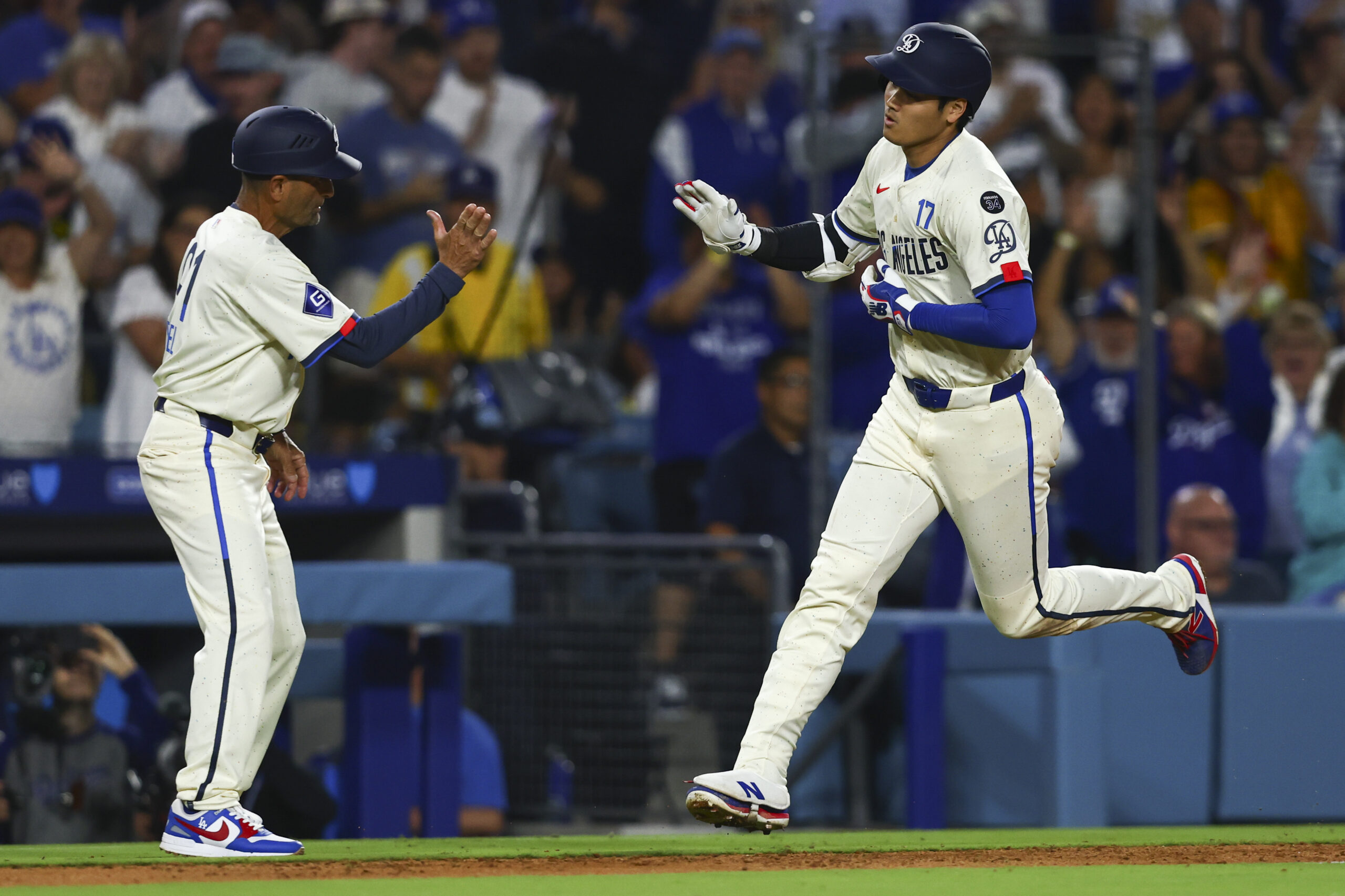 Dodgers designated hitter Shohei Ohtani celebrates with third base coach...