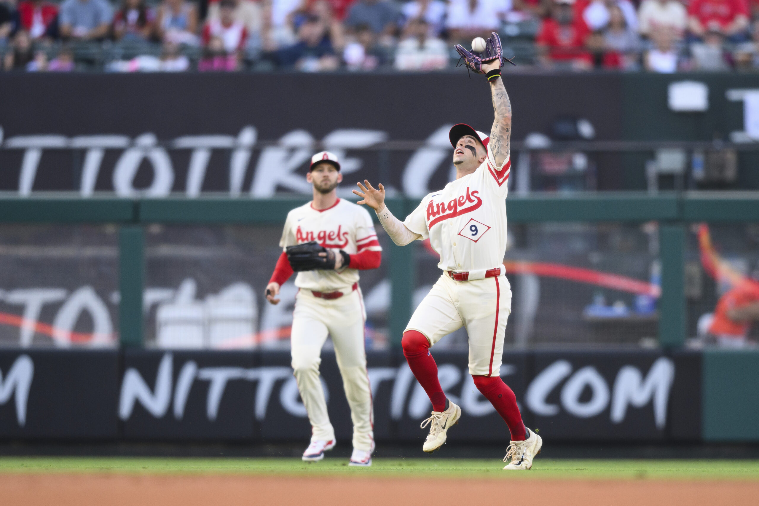 Angels shortstop Zach Neto, right, makes a catch during the...
