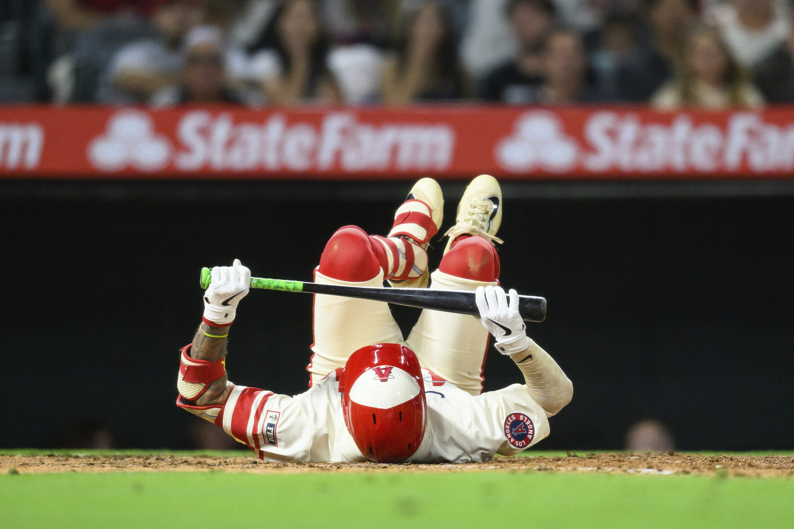 The Angels’ Zach Neto falls to the ground after striking...