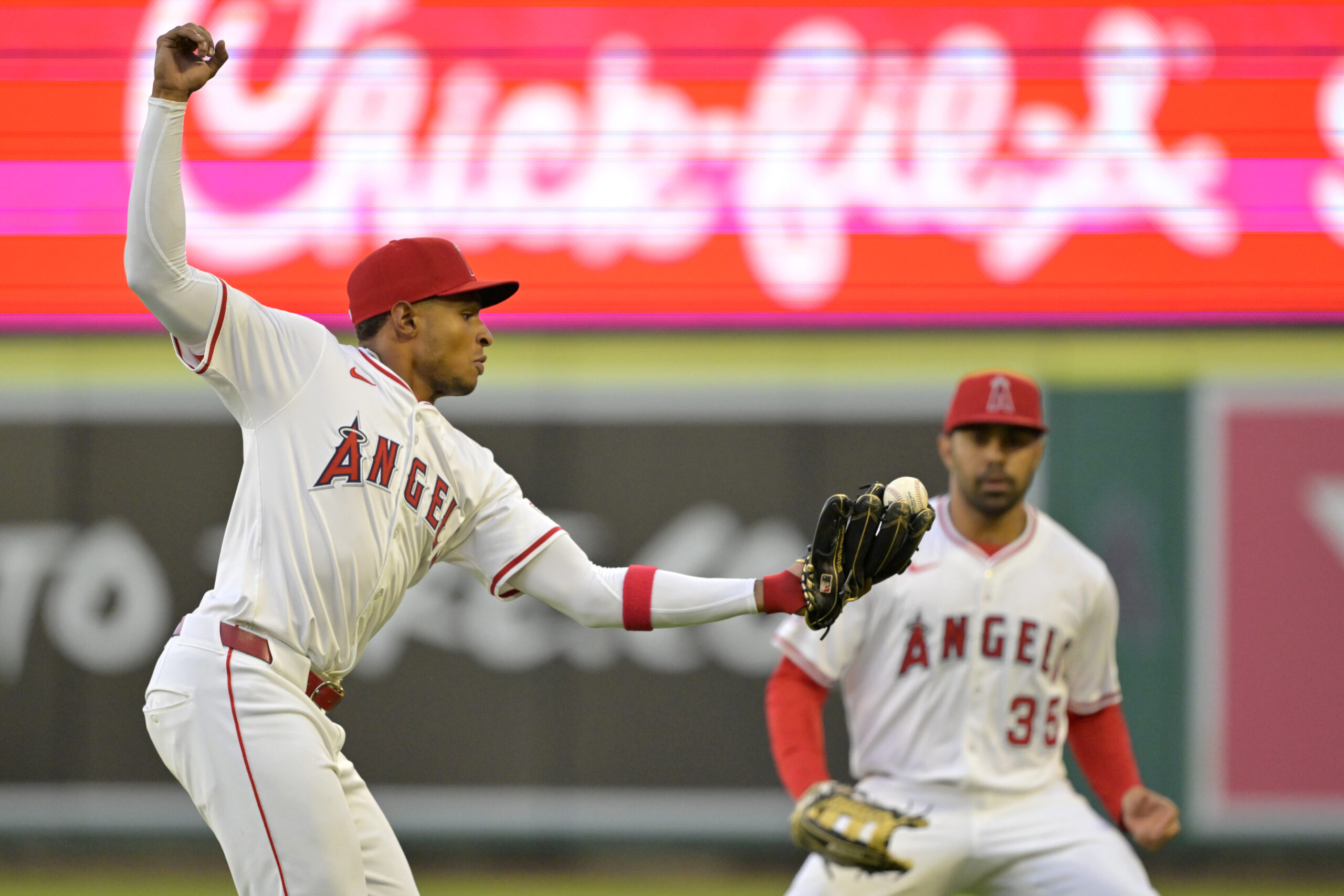 Angels second baseman Christian Moore, left, catches a fly ball...
