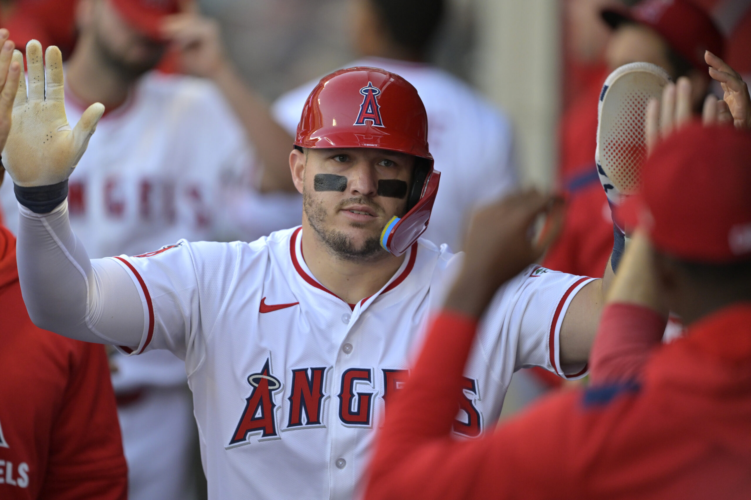Angels star Mike Trout is greeted in the dugout after...