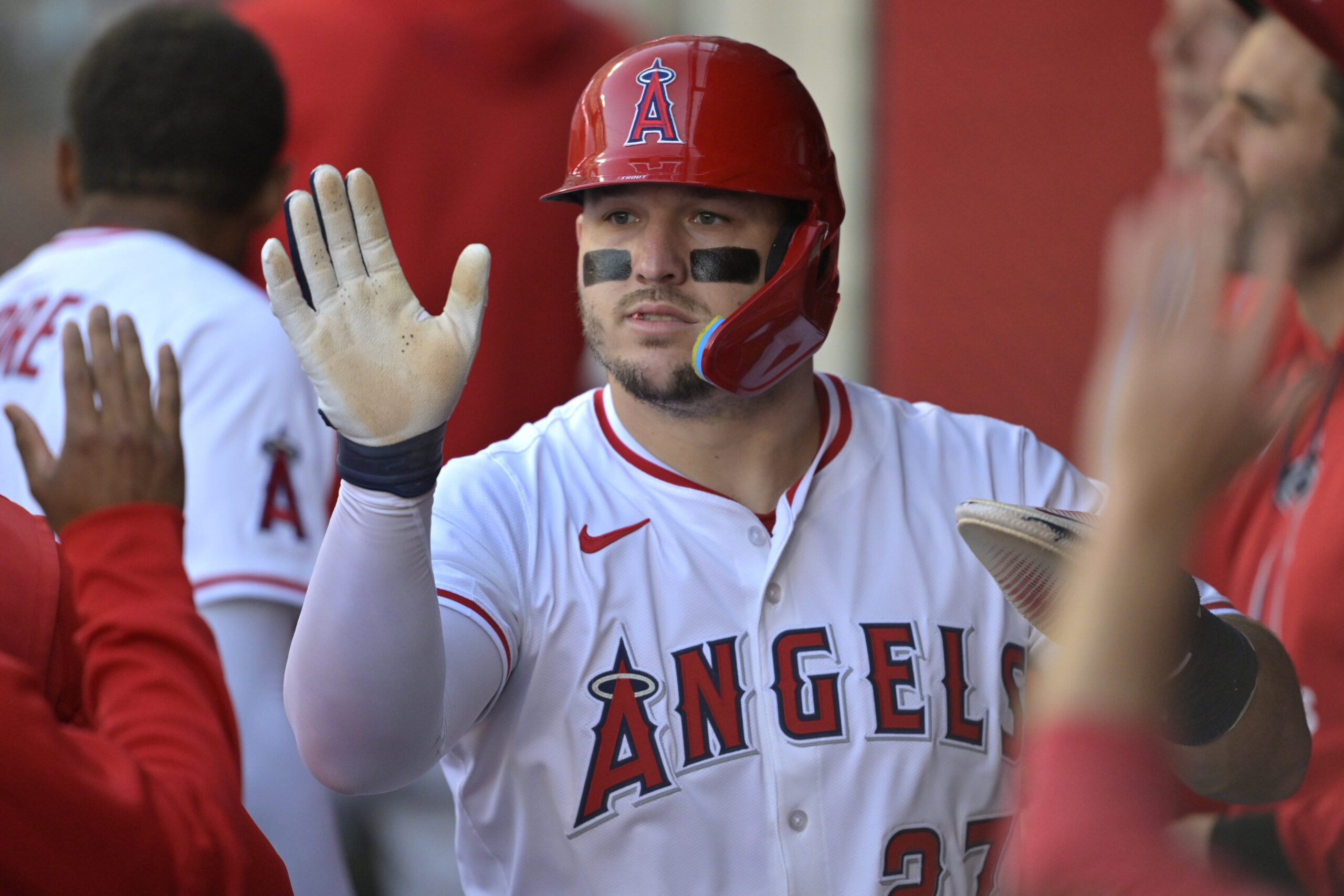 Angels star Mike Trout is greeted in the dugout after...