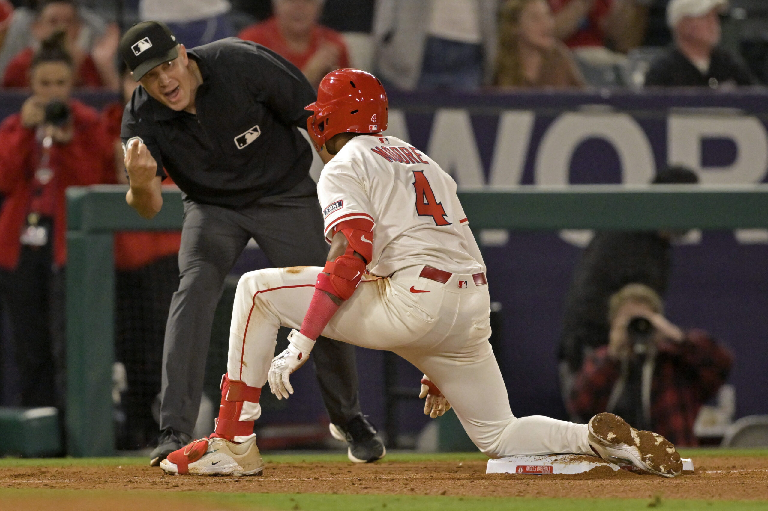 Umpire Chris Segal, left, tells Angels rookie Christian Moore that...