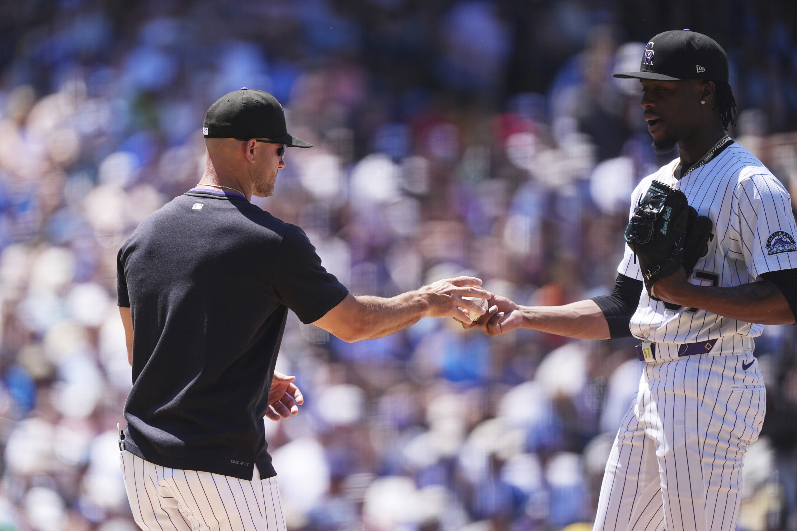 Colorado Rockies interim manager Warren Schaeffer, left, takes the ball...