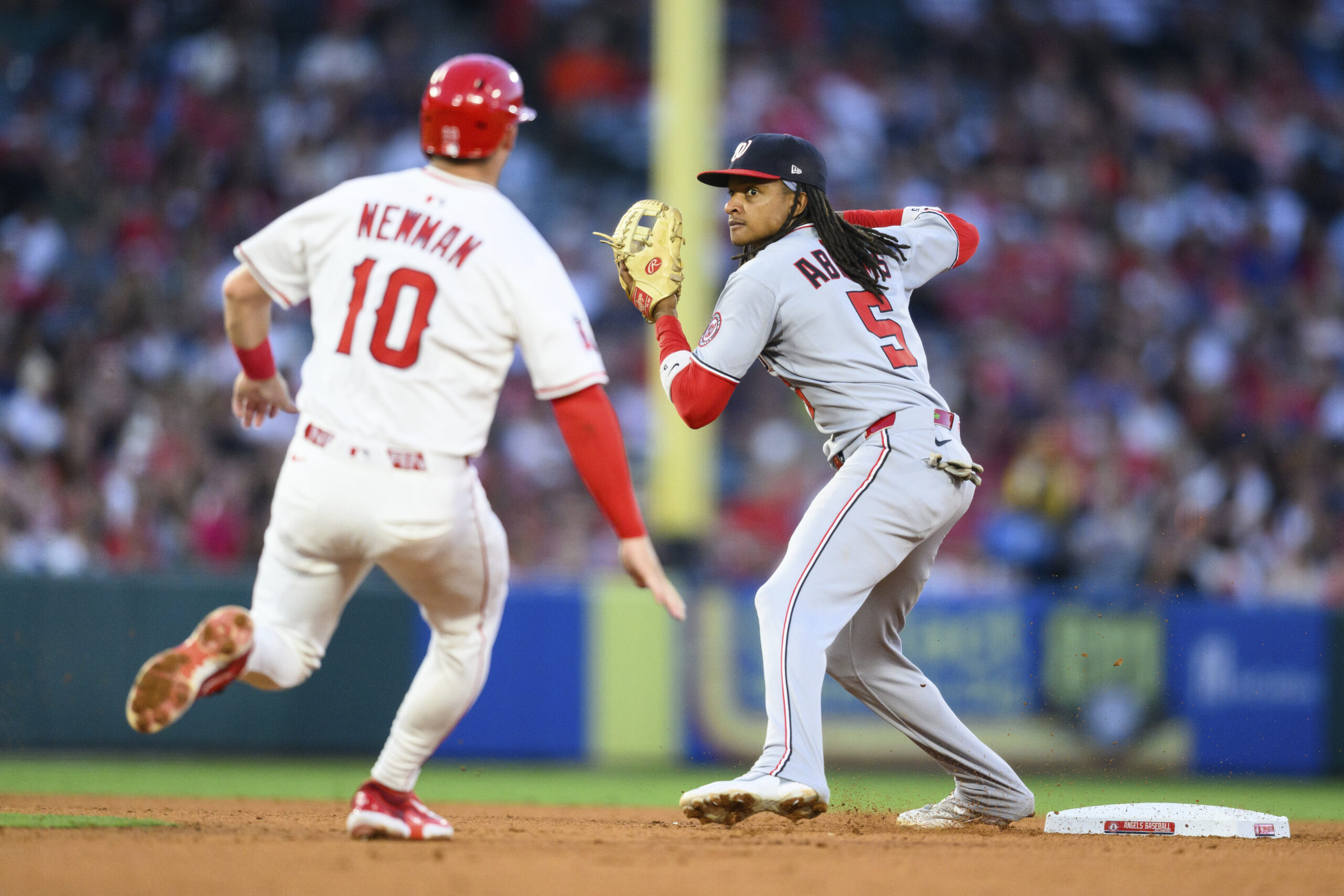 Washington Nationals shortstop CJ Abrams, right, throws to first base...