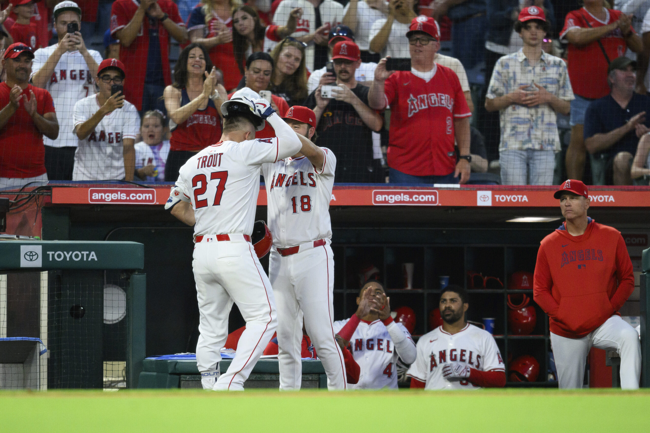 Angels’ Mike Trout (27) is greeted by teammates after hitting...