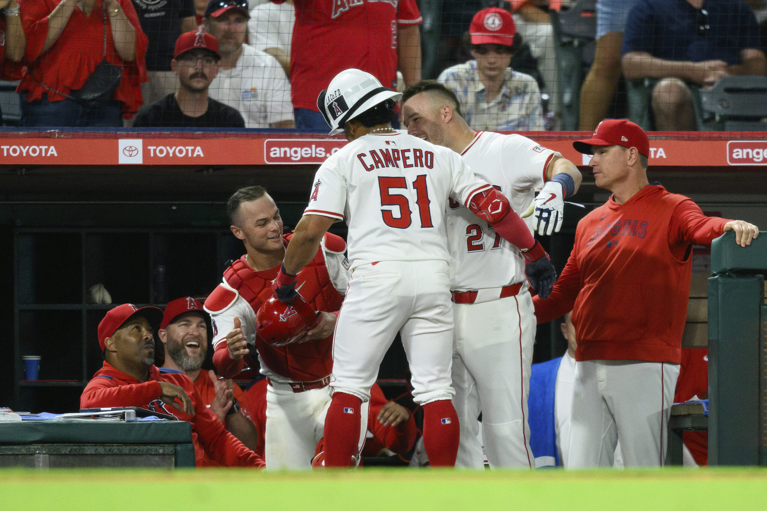 Angels’ Gustavo Campero (51) is greeted by teammates after hitting...