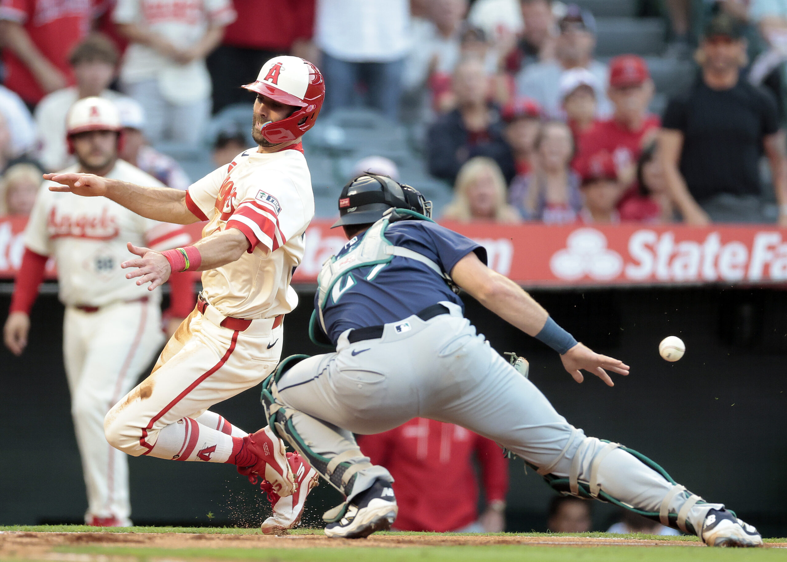 The Angels’ Chris Taylor, left, scores safely past Seattle Mariners...