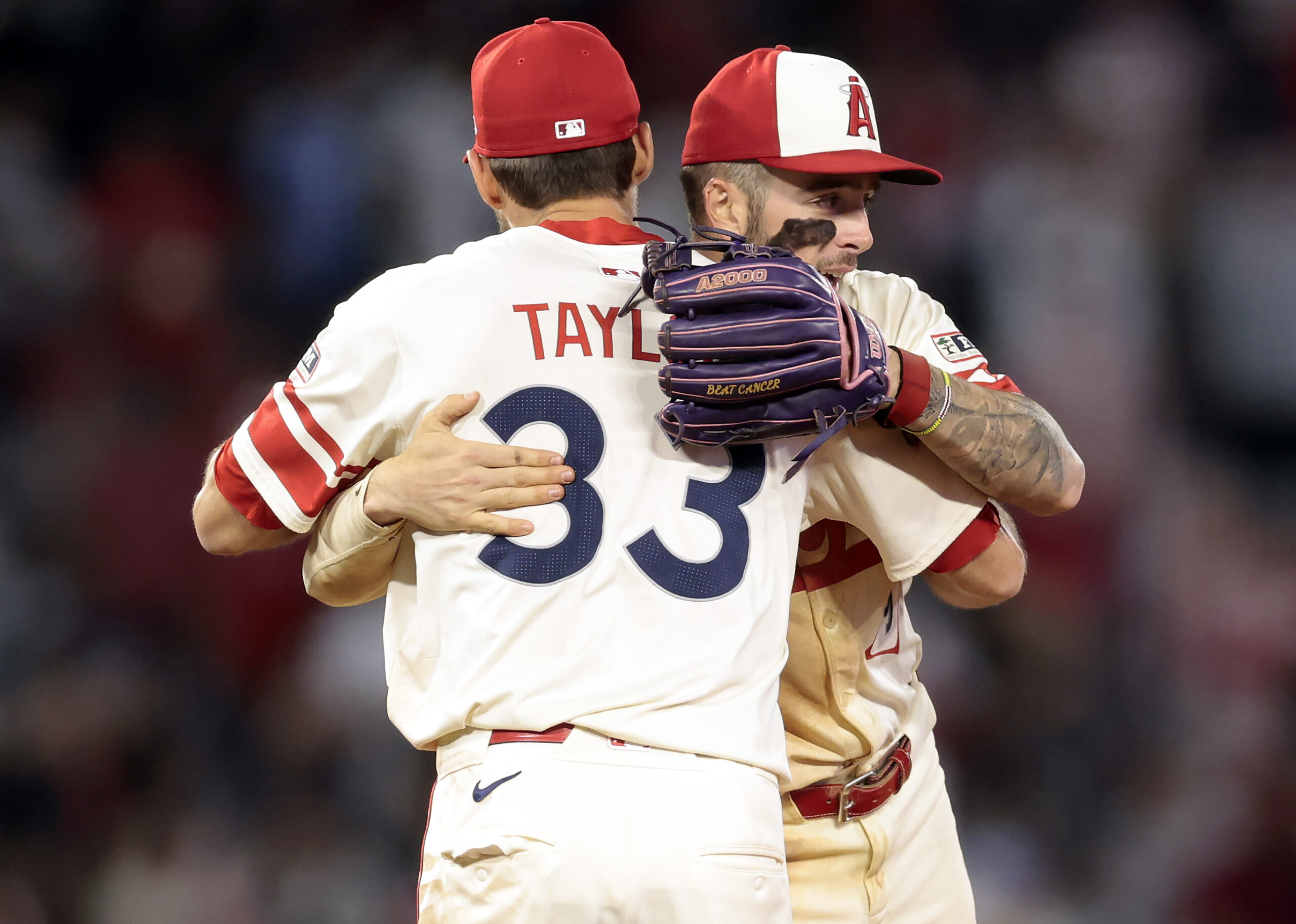 Angels infielders Chris Taylor, left, and Zach Neto embrace after...