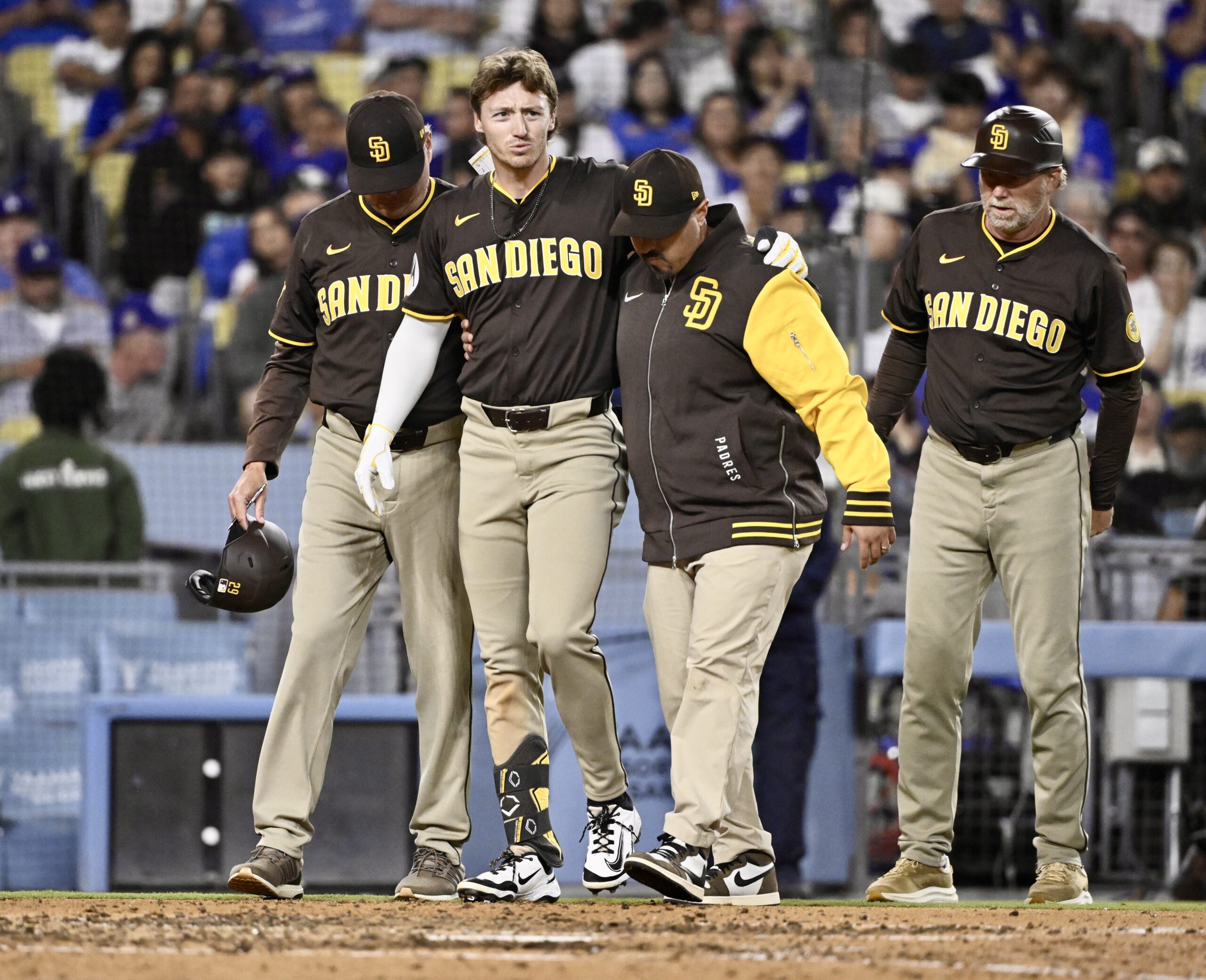 The San Diego Padres’ Bryce Johnson, center, is helped off...