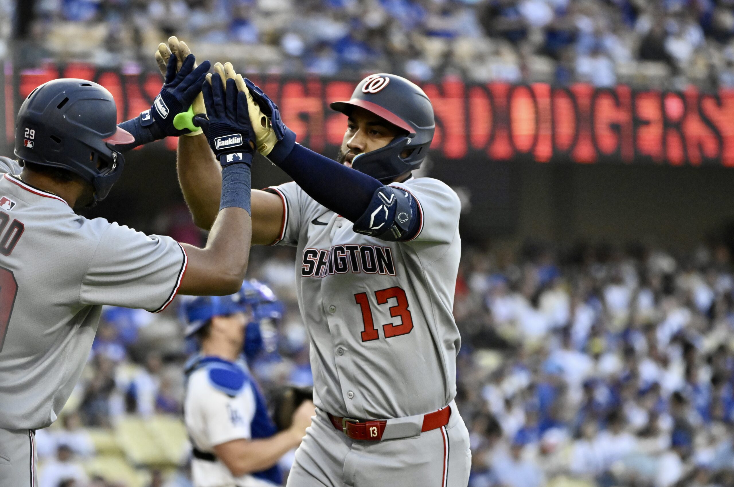 The Washington Nationals’ Amed Rosario, right, high-fives teammate James Wood...