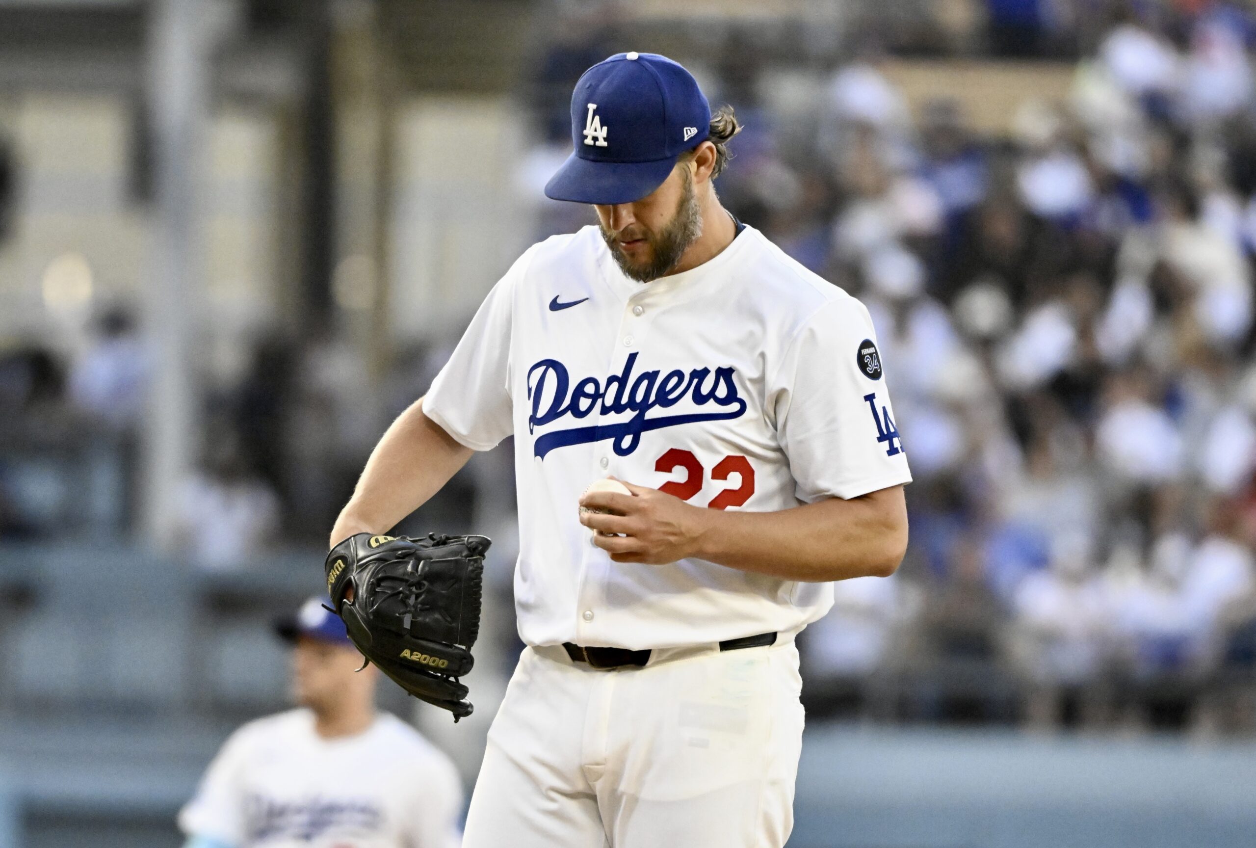 Dodgers starting pitcher Clayton Kershaw looks at a baseball after...