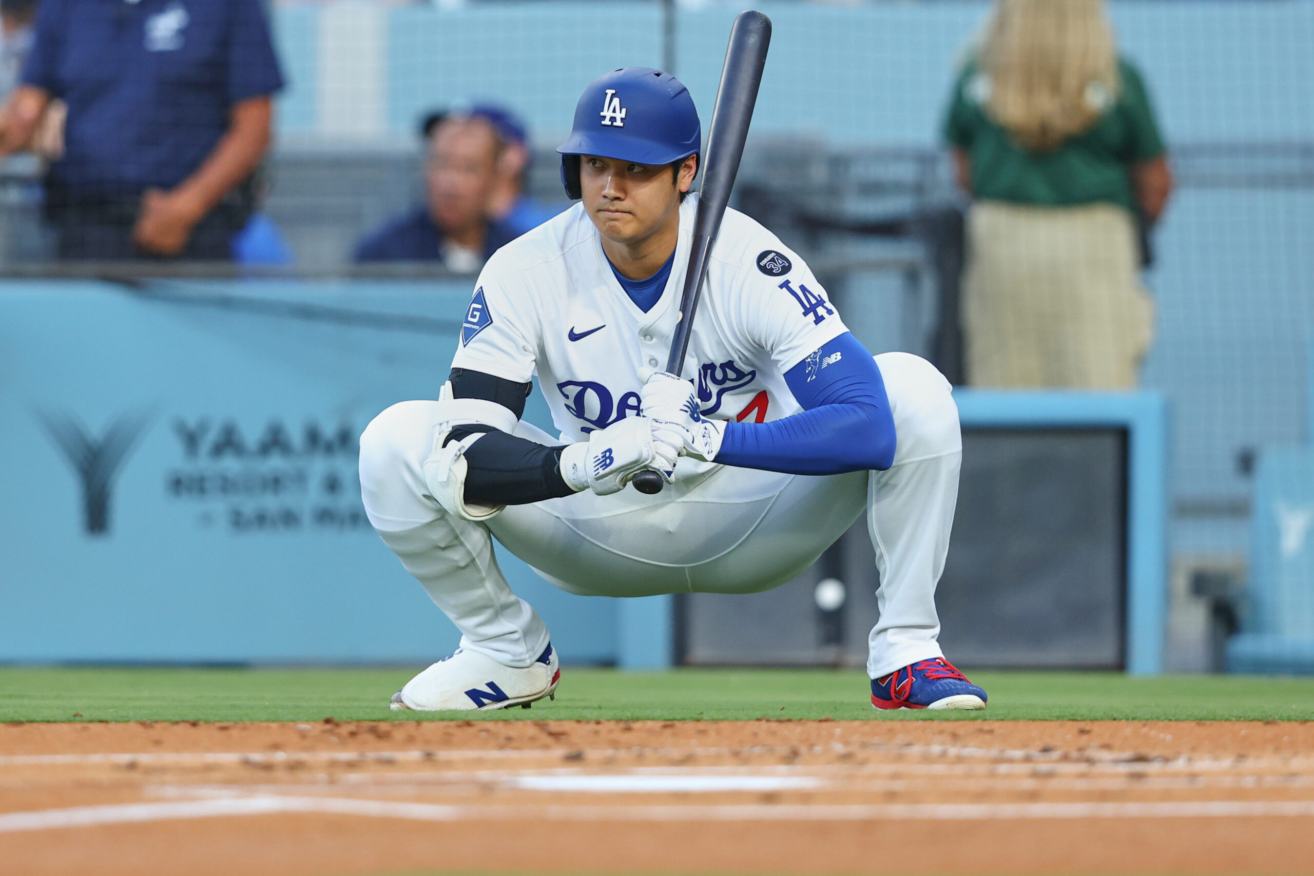 Dodgers star Shohei Ohtani looks on while squatting during the...