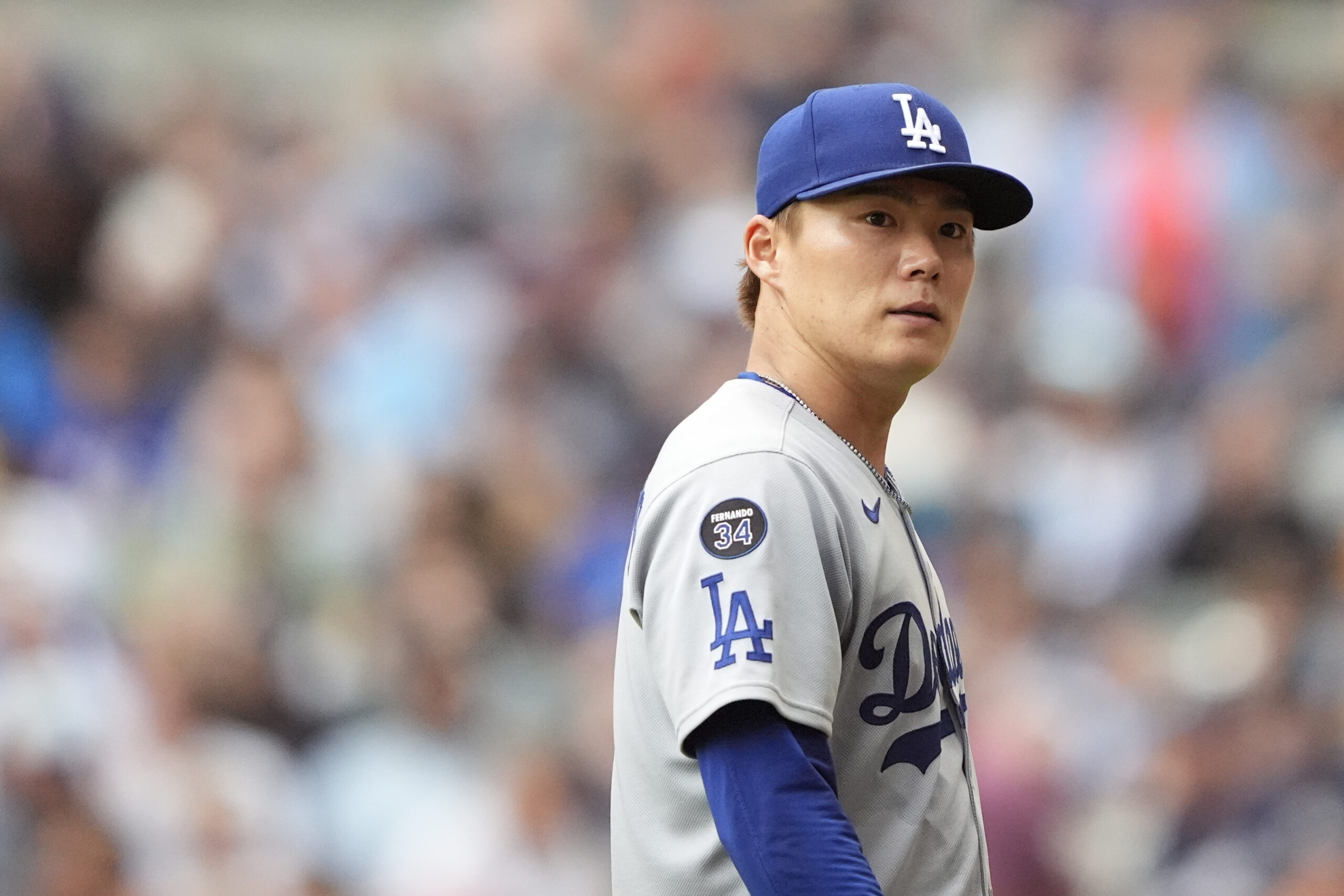 Dodgers starting pitcher Yoshinobu Yamamoto looks on after being taken...