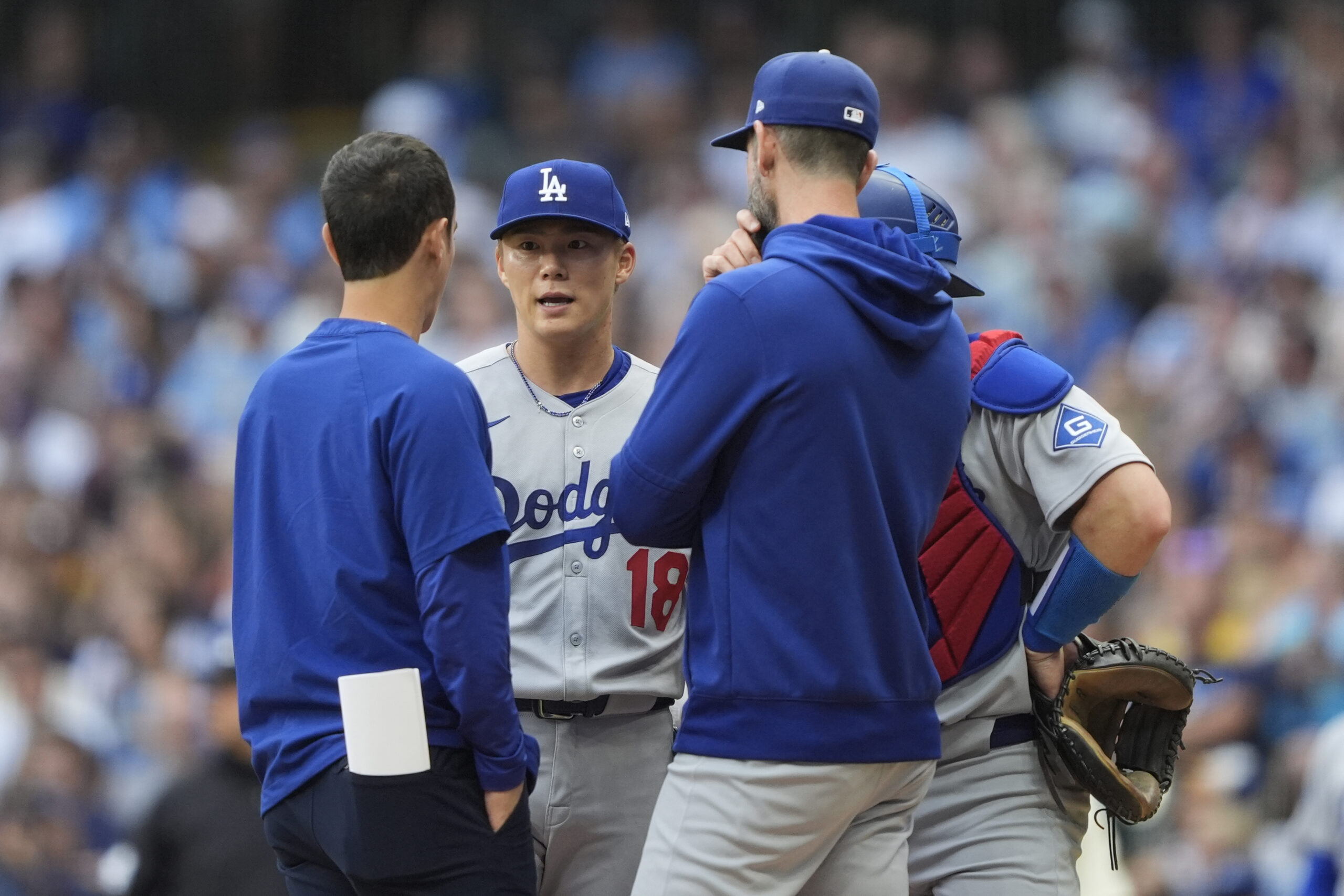 Dodgers starting pitcher Yoshinobu Yamamoto (18) talks with coaches on...