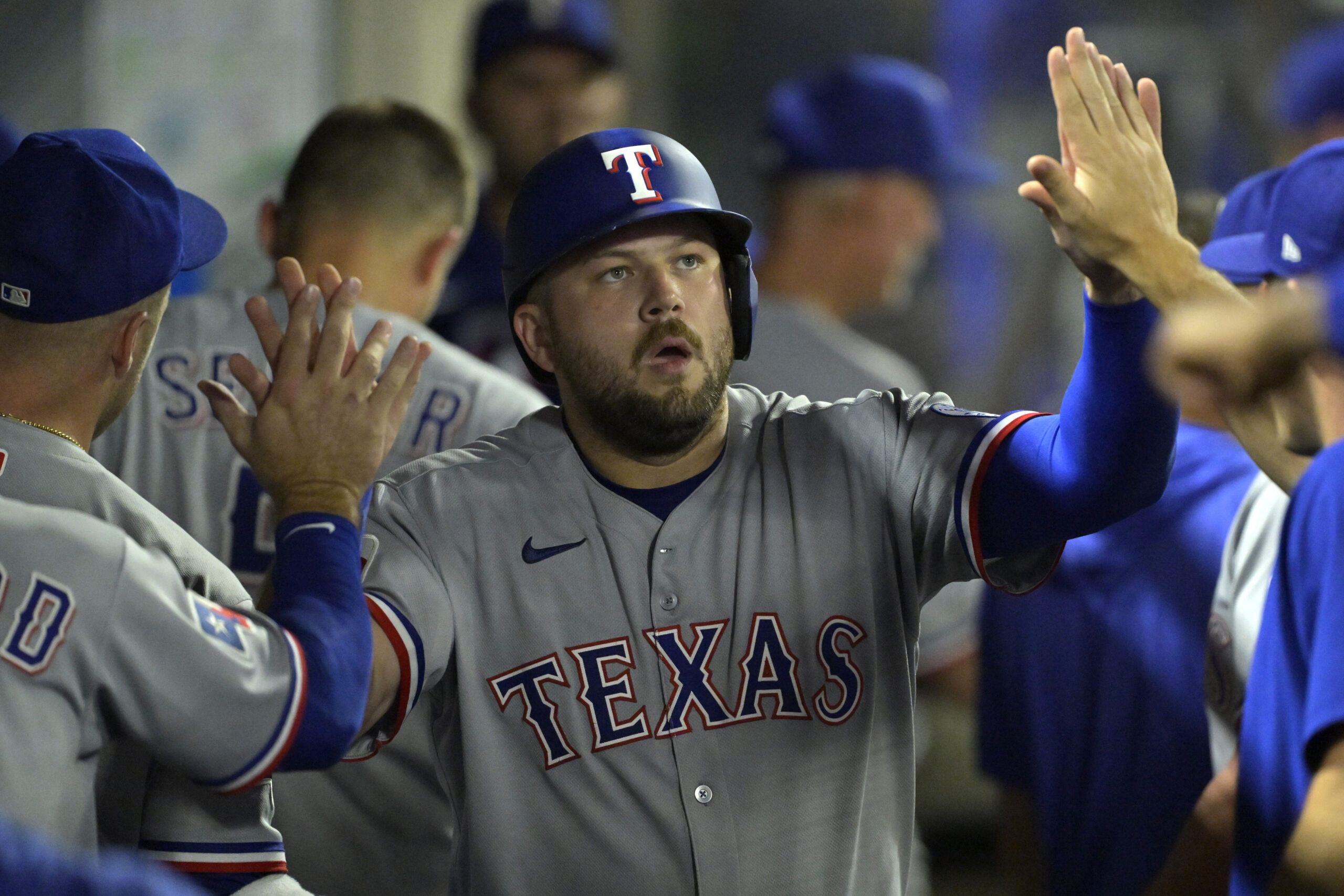 The Texas Rangers’ Jake Burger is greeted in the dugout...