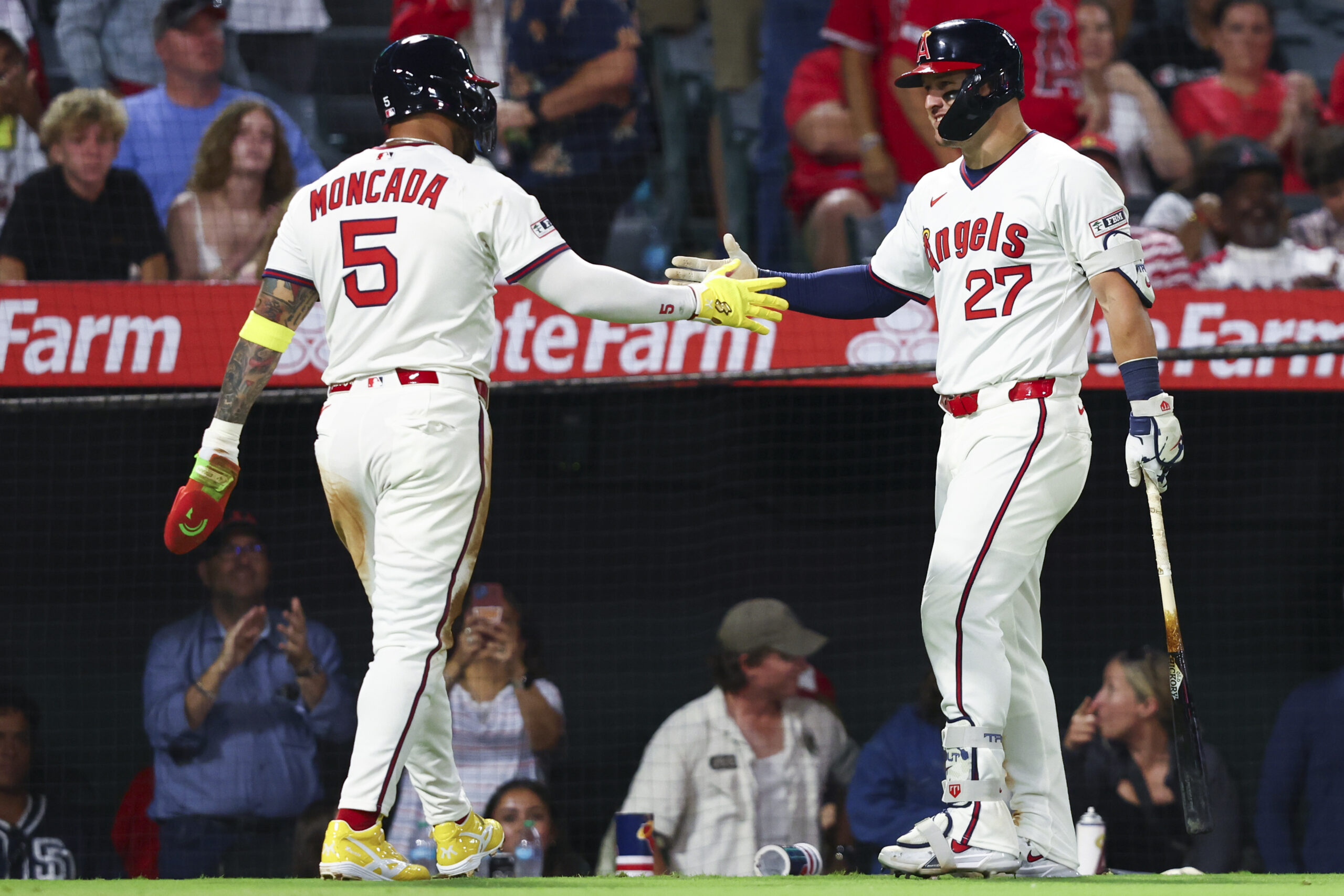 Angels’ Yoán Moncada (5) and designated hitter Mike Trout (27)...