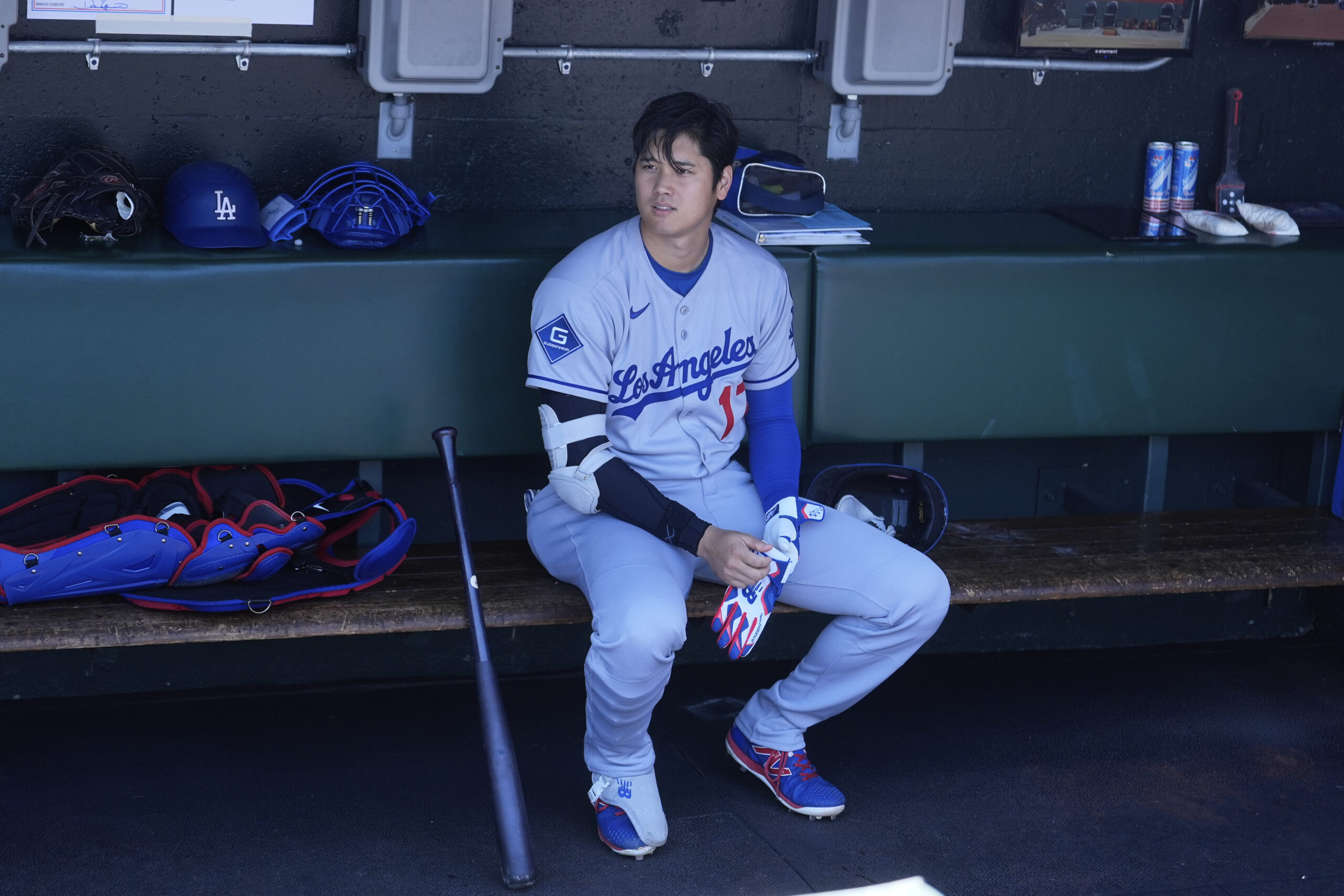 Dodgers’ Shohei Ohtani sits in the dugout before a baseball...