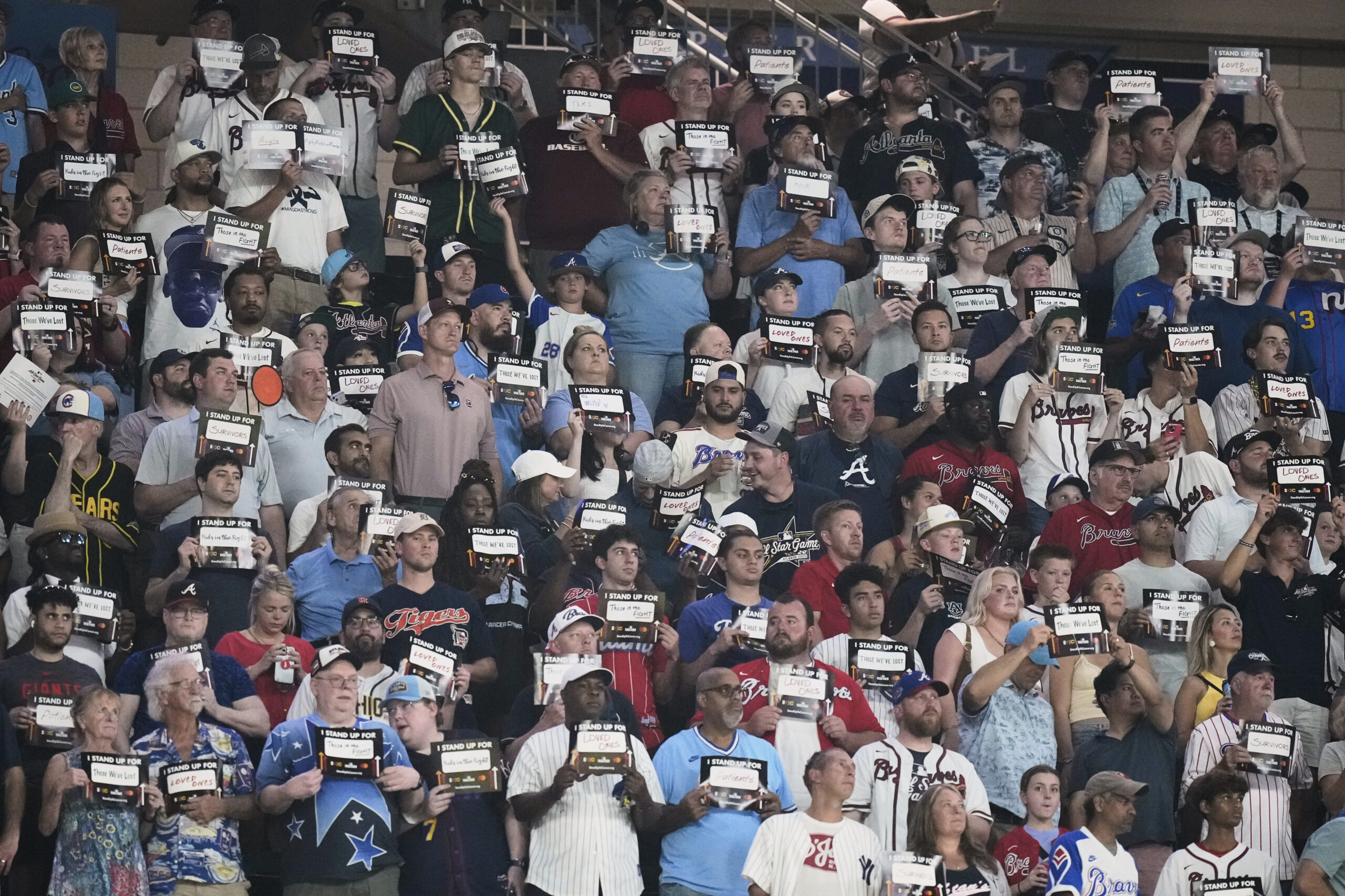 Fans participate in a stand-up to cancer event during the...