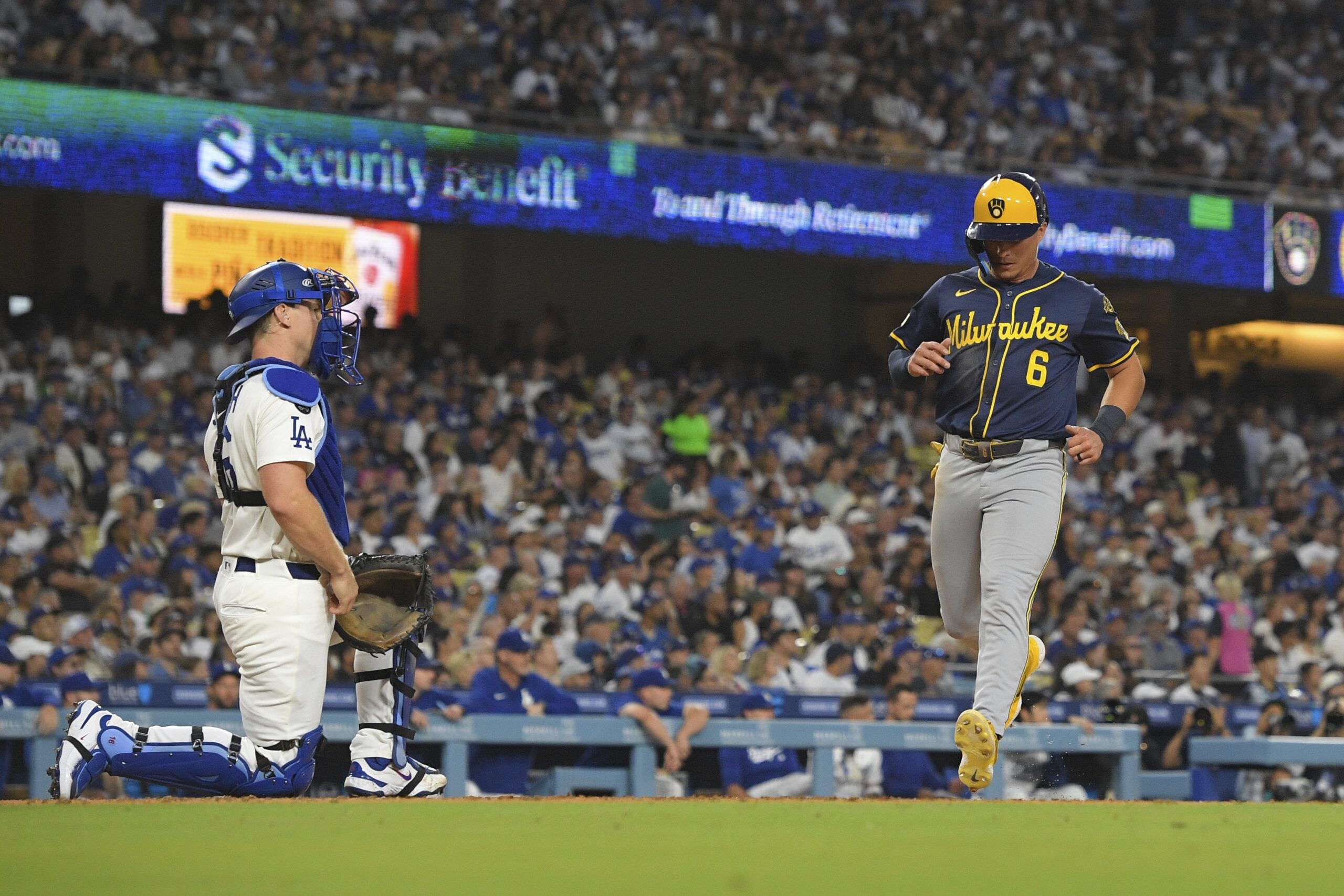 The Milwaukee Brewers’ Isaac Collins, right, scores on a double...