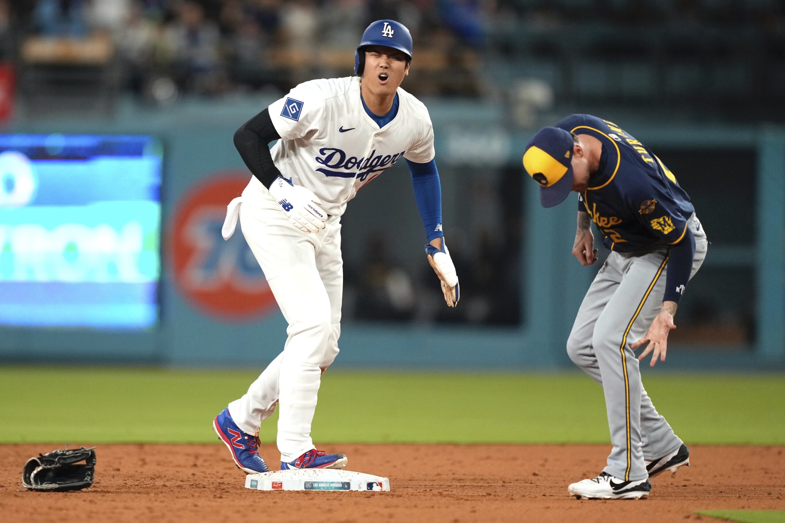 Dodgers star Shohei Ohtani, left, winces after colliding with Milwaukee...